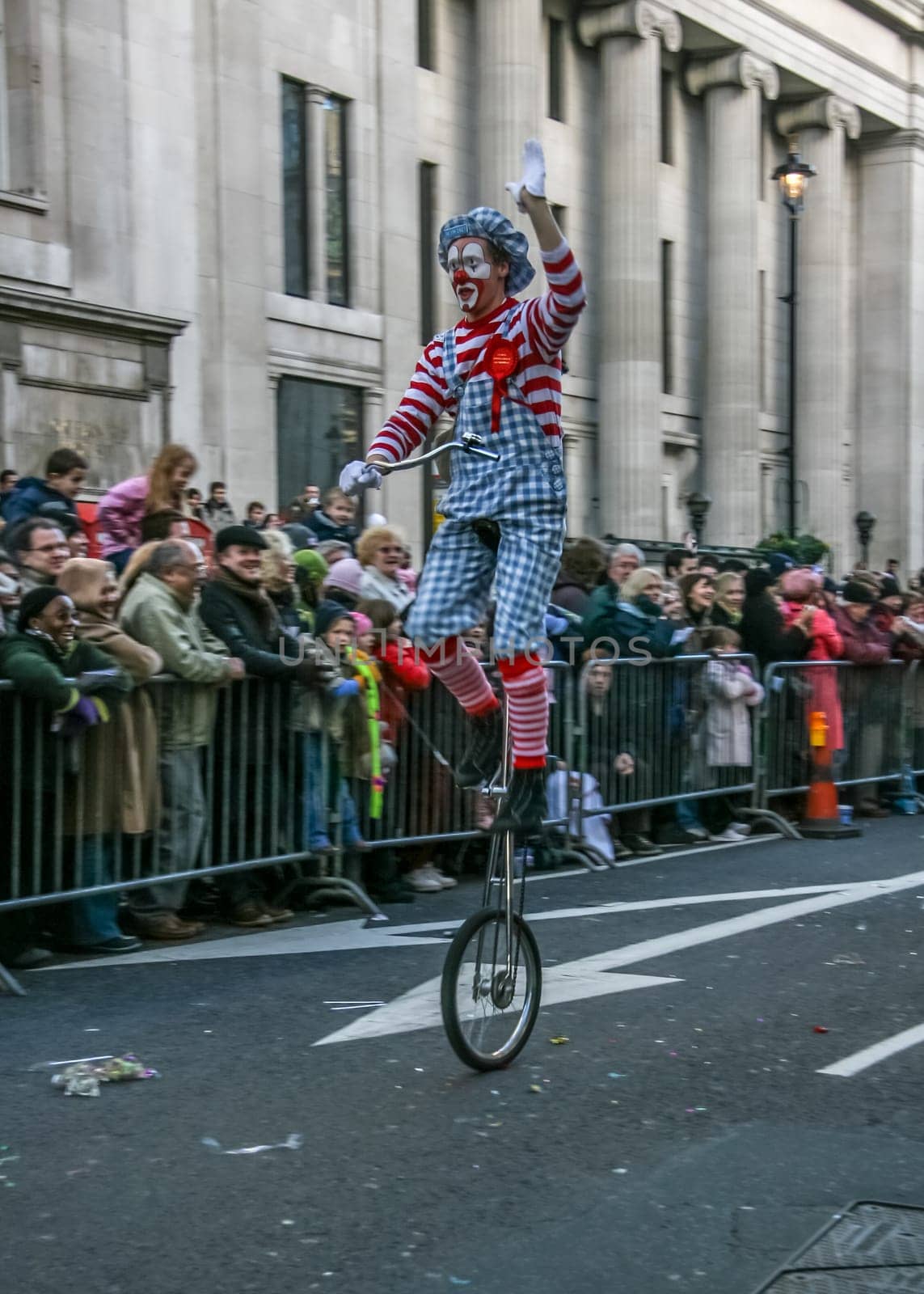 London, United Kingdom - January 1, 2007: Man in clown costume rides unicycle, and waves to cheering crowd, during New Year's Day Parade. by Ivanko