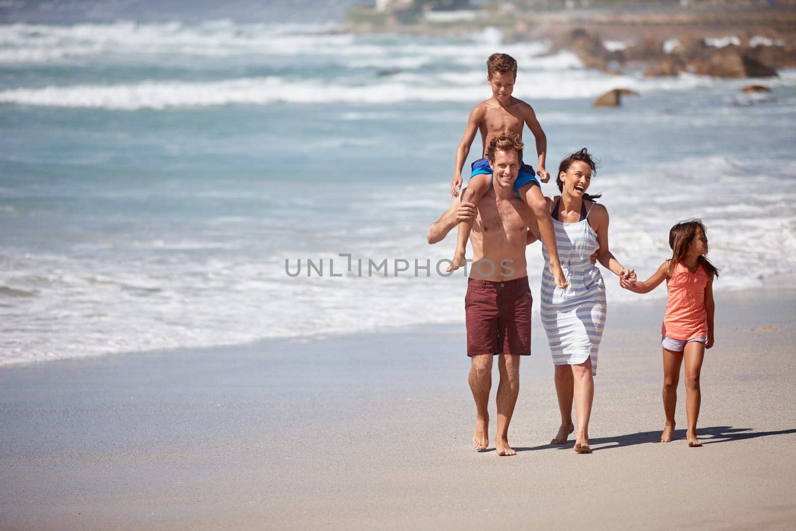 The perfect family getaway. a family walking along the beach. by YuriArcurs