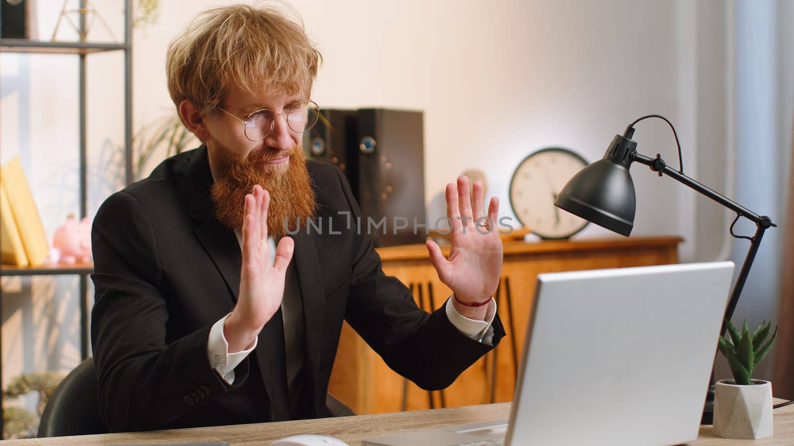 Young businessman working on laptop computer at home office desk talk on online communication video call with employee, boss. Manager man freelancer support services looking at webcam of computer