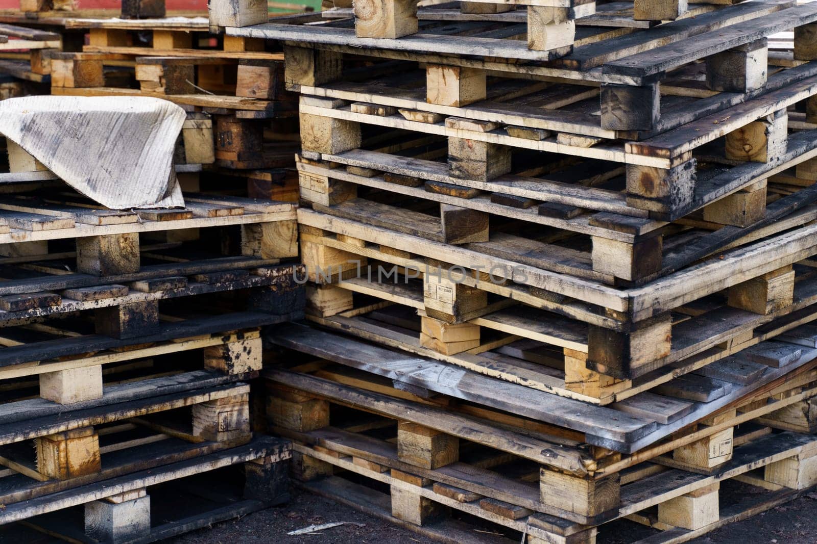 Old wooden pallets stacked on the ground. Industrial background.
