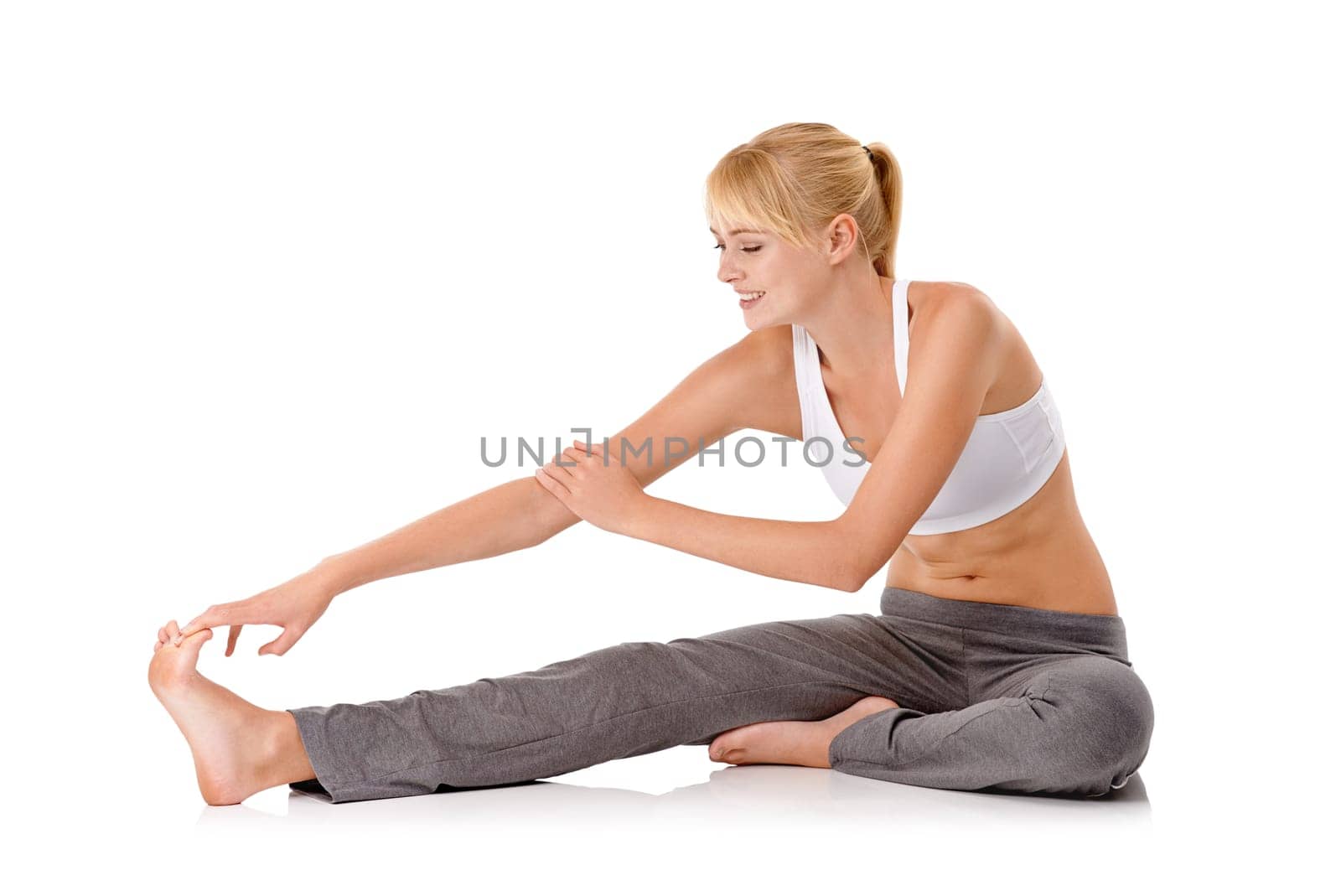 Limbering up. Full-length shot of a young woman exercising on the floor isolated on white