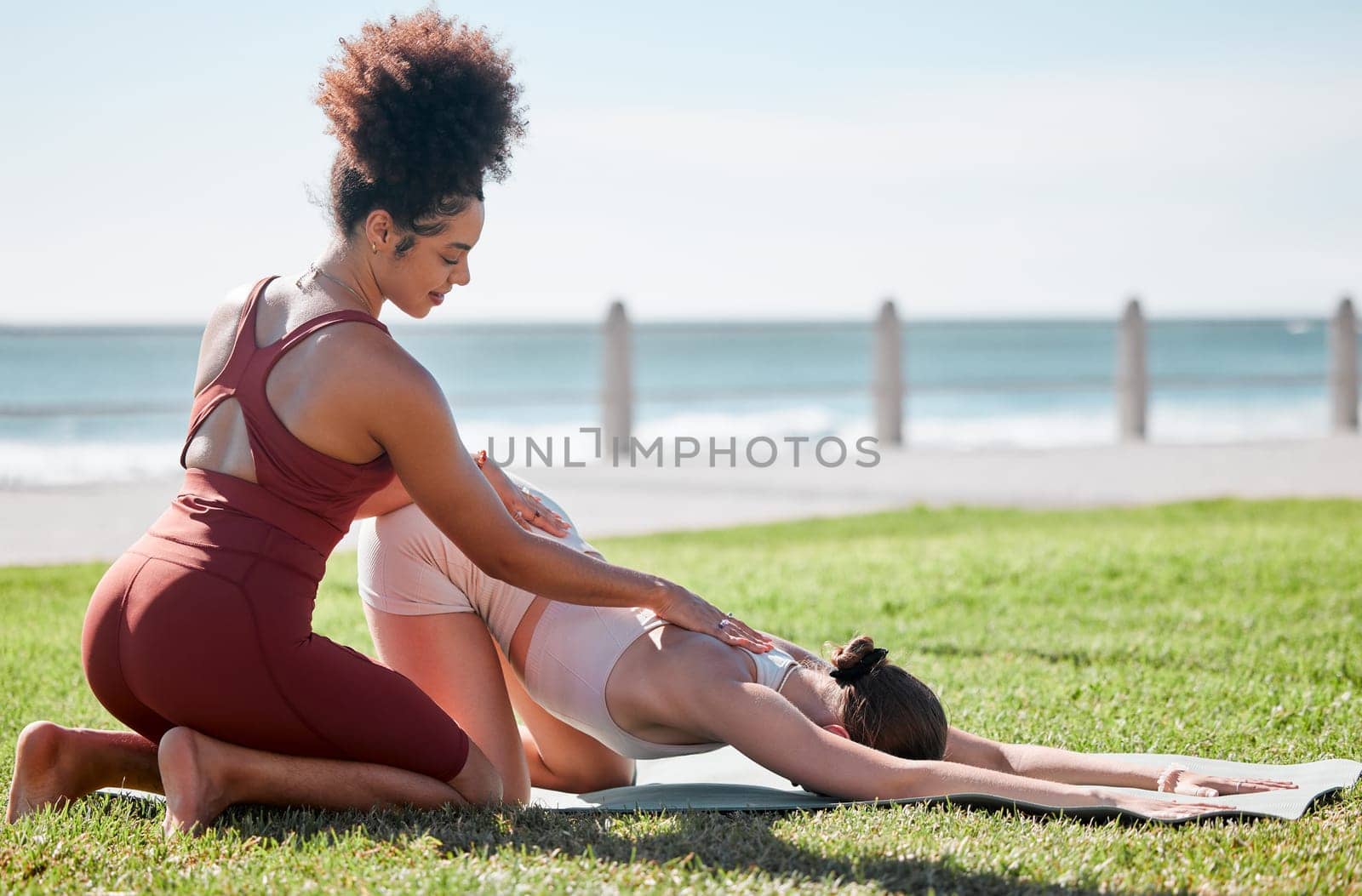 Help, fitness and women doing yoga at park for a warm up, exercise and stretching support in Spain. Health, training and personal trainer with a girl for flexibility during pilates workout in nature by YuriArcurs