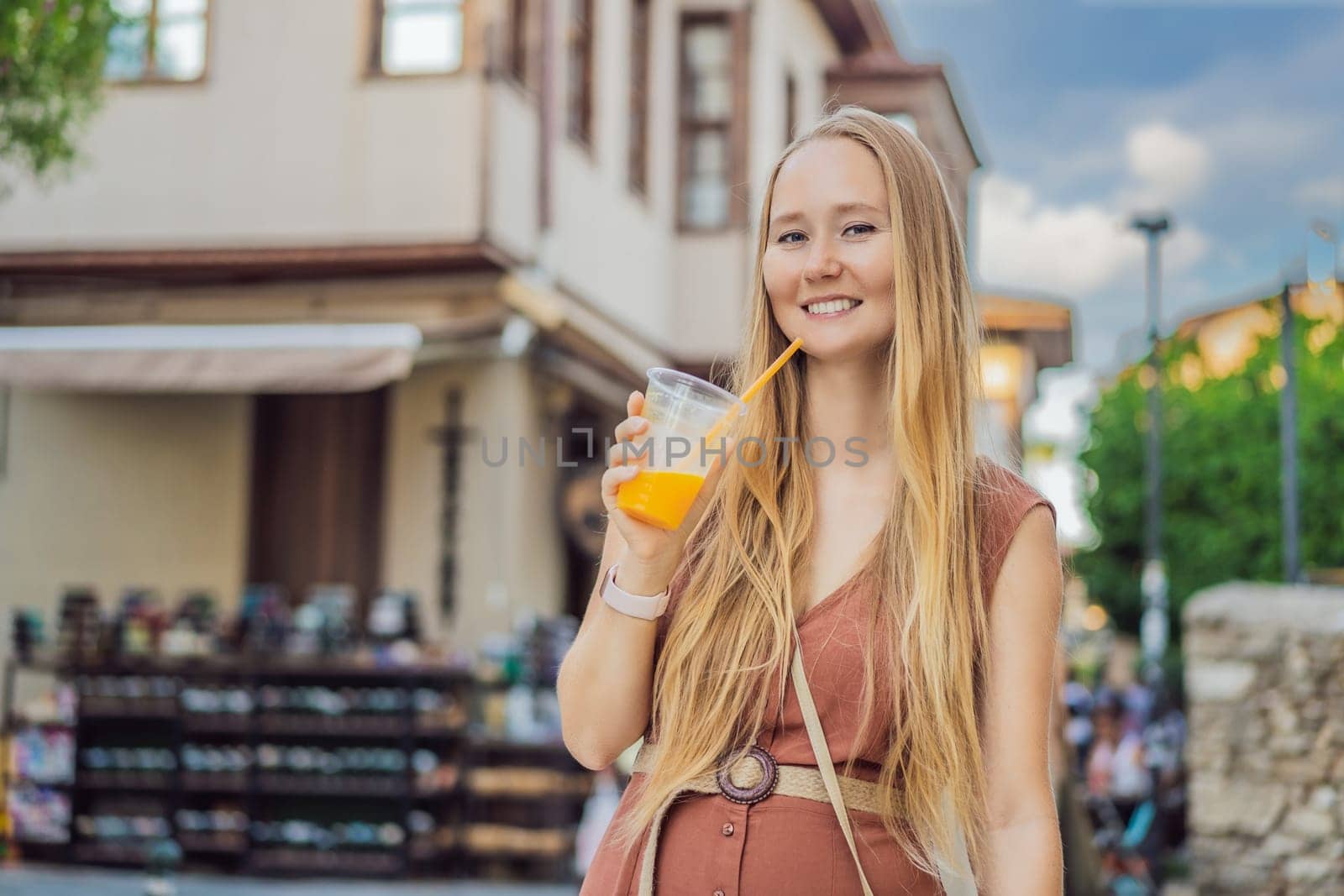 Happy woman tourist with fresh juice on background of old street of Antalya. female tourist traveler discover interesting places and popular attractions and walks in the old city Kalechi of Antalya, Turkey. Turkiye.