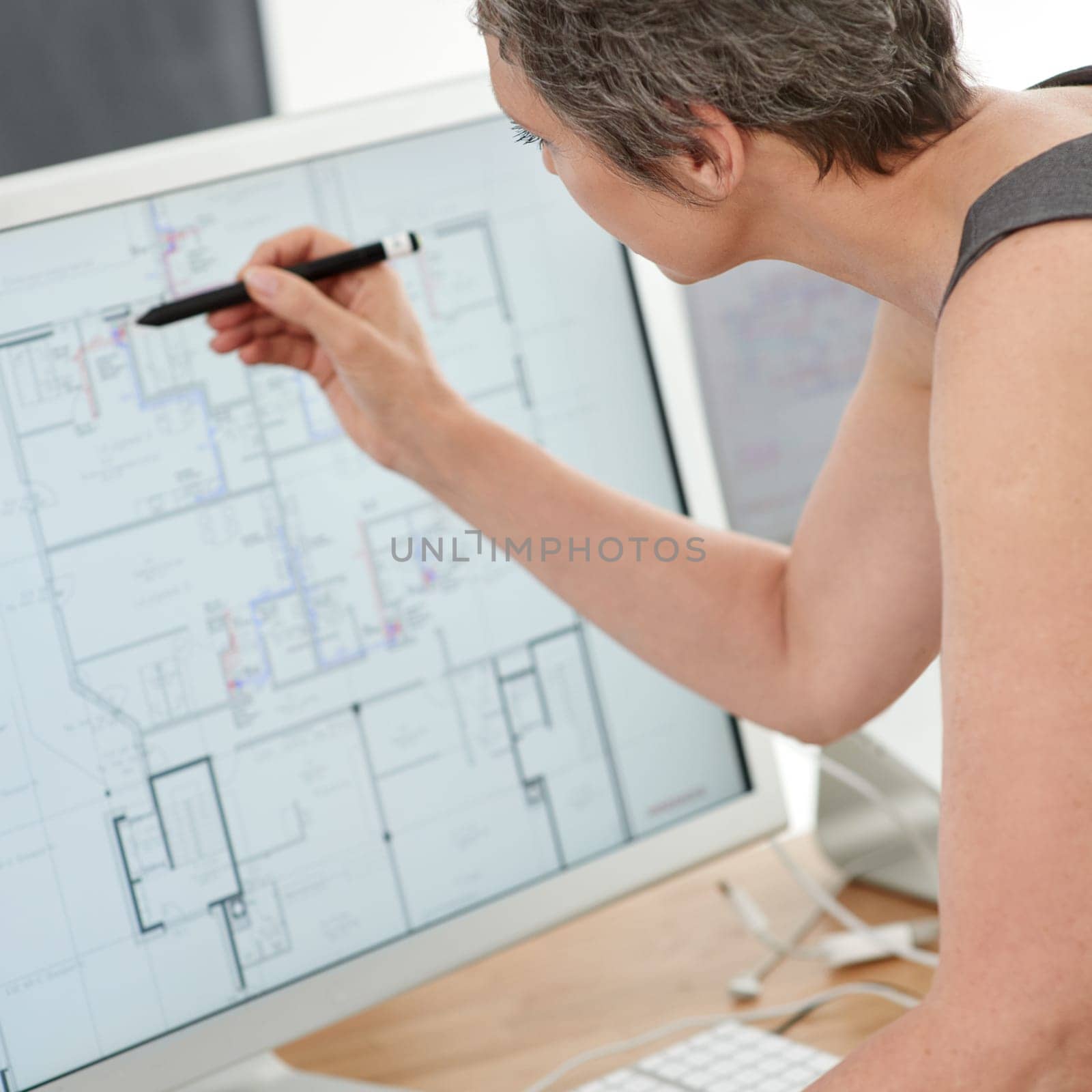Utilizing modern technology to draw up building plans. A mature female architect working on building plans on her touchscreen computer. by YuriArcurs