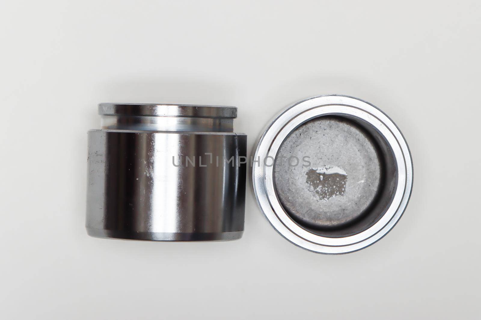 Two metal cylindrical pistons, machine repair parts. A set of spare parts for servicing the braking system of a vehicle. Details on white background, copy space available.