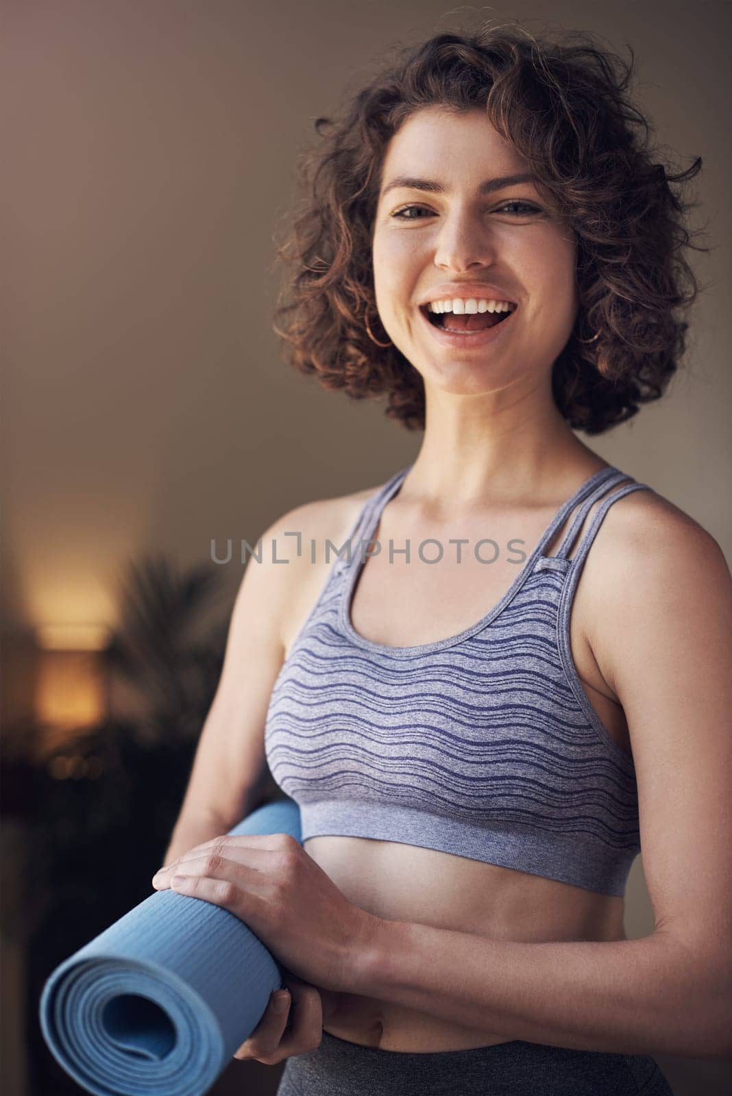 I didnt choose the yoga life, it chose me. Cropped portrait of an attractive young woman standing alone and holding her yoga mat before an indoor yoga session. by YuriArcurs