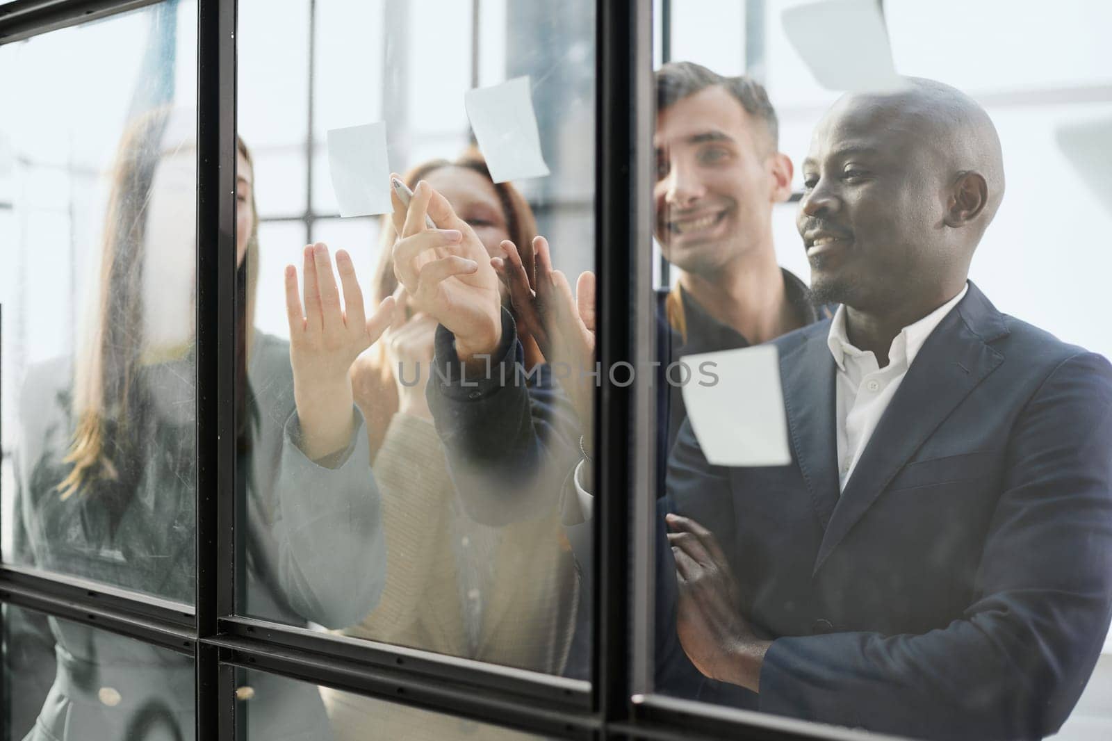 Creative business team looking at sticky notes on glass window