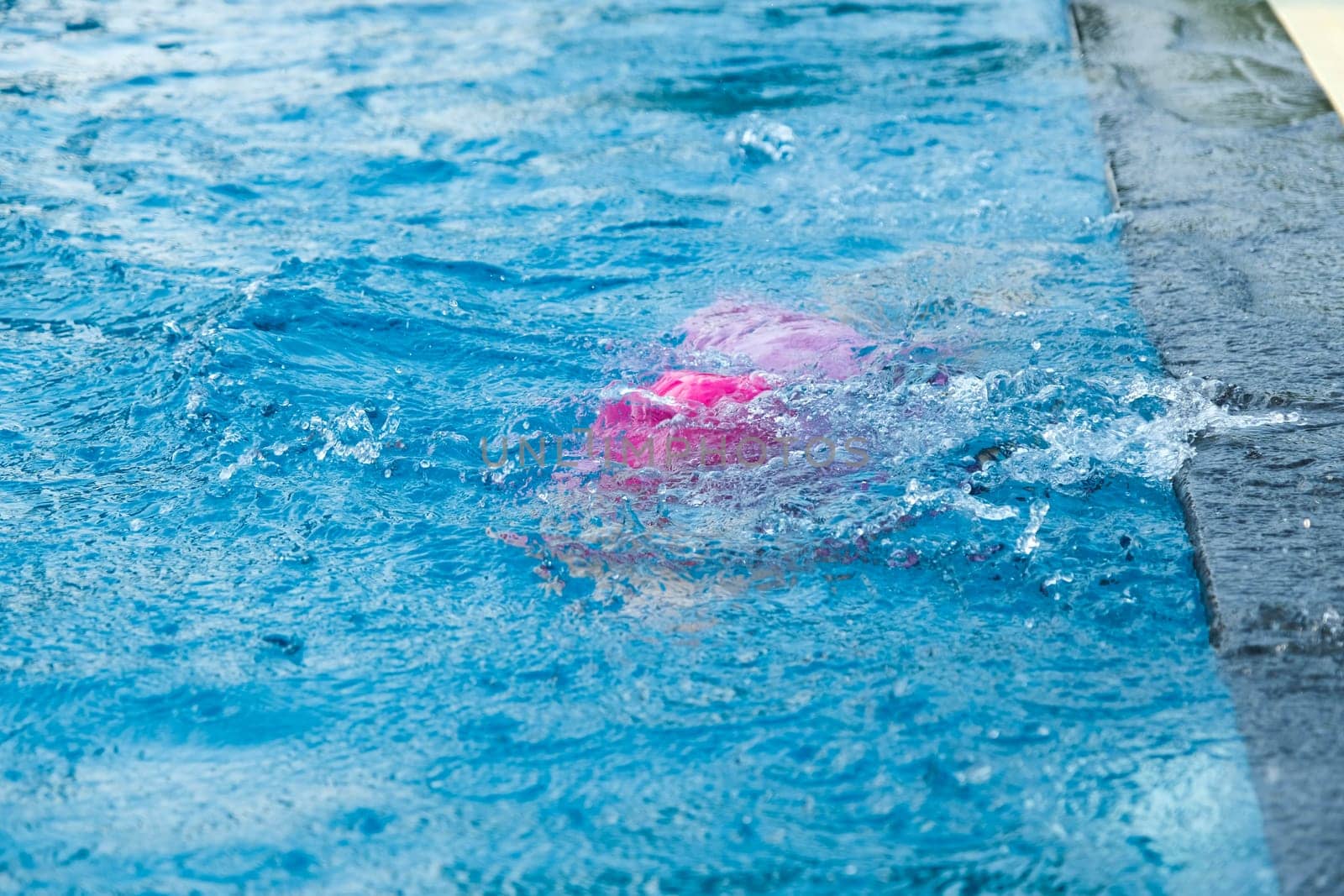 Little girl practicing swimming in the pool. Happy children swimming and playing in the water. summer vacation concept. by TEERASAK