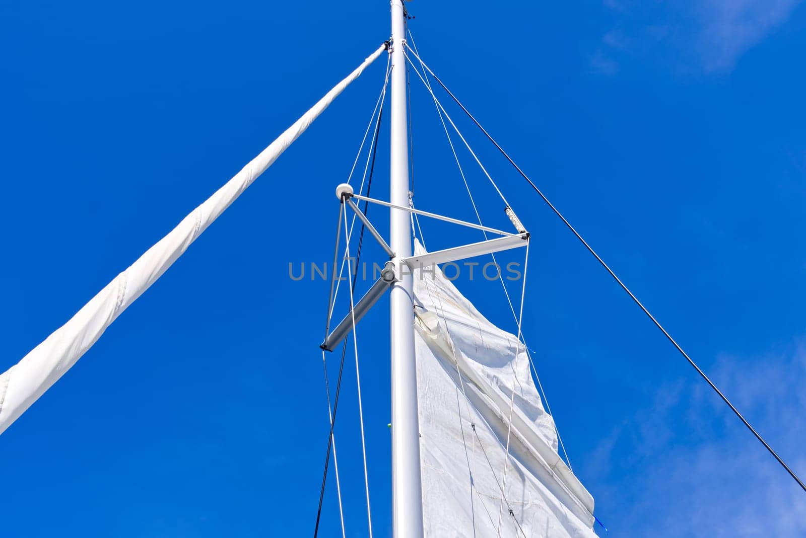 Raising the sail on a yacht. Young man captan lifting the sail of catamaran yacht during cruising. luxury sailing yacht, with sails being raised by rigging