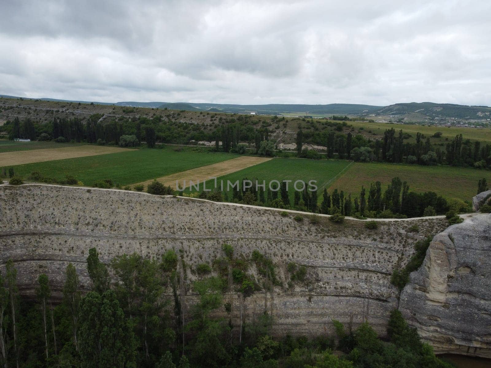 Aerial viev of lush green farm field with rocky cliffs in the distance. beauty of rural areas and the agricultural process. by panophotograph