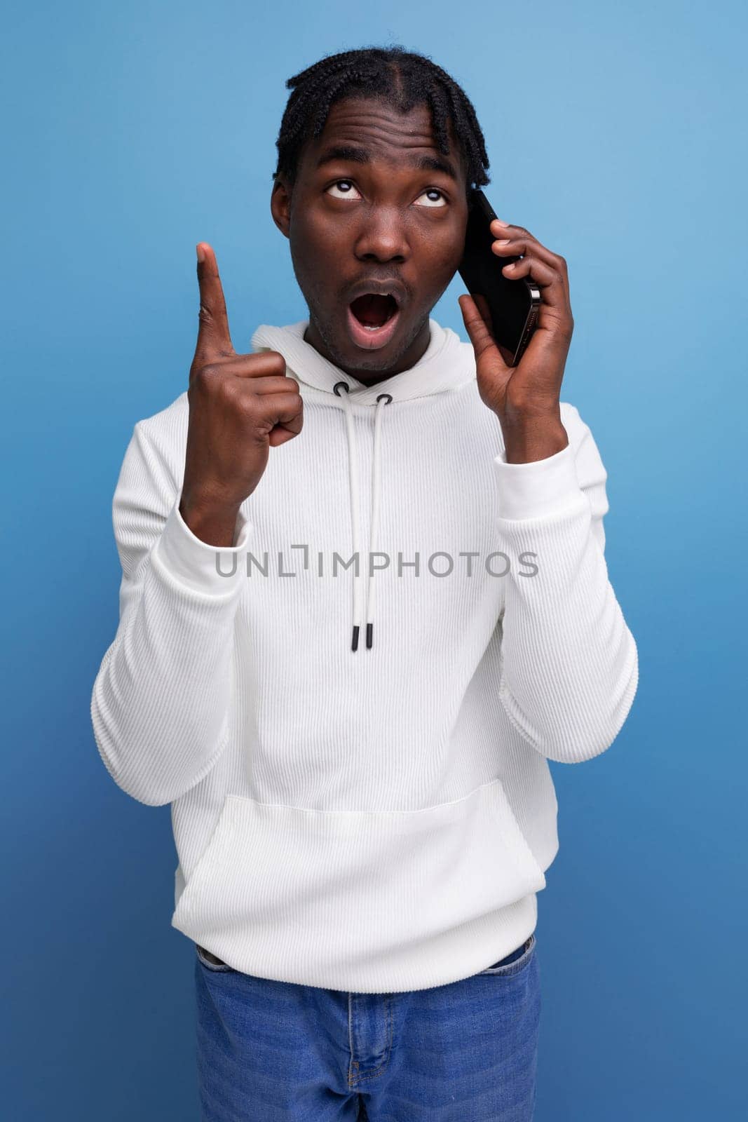 smart young african guy in a white sweatshirt communicates on a mobile phone.