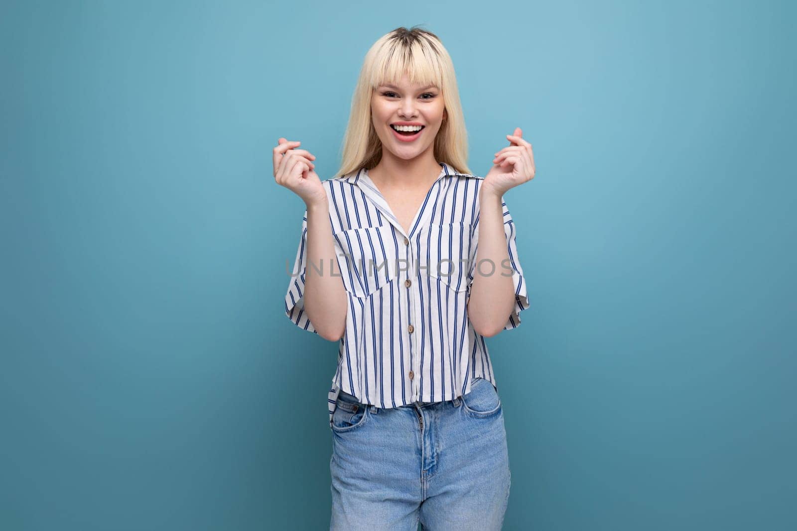 positive energetic blond young lady in casual outfit with smartphone in studio.