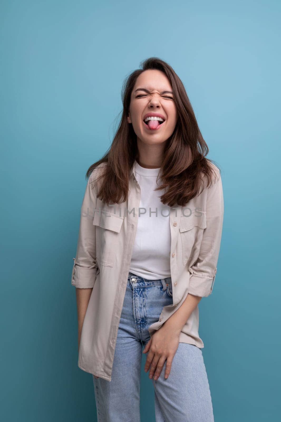 cheerful positive brunette 30 year old female person dressed in a shirt and jeans laughs and makes a face.