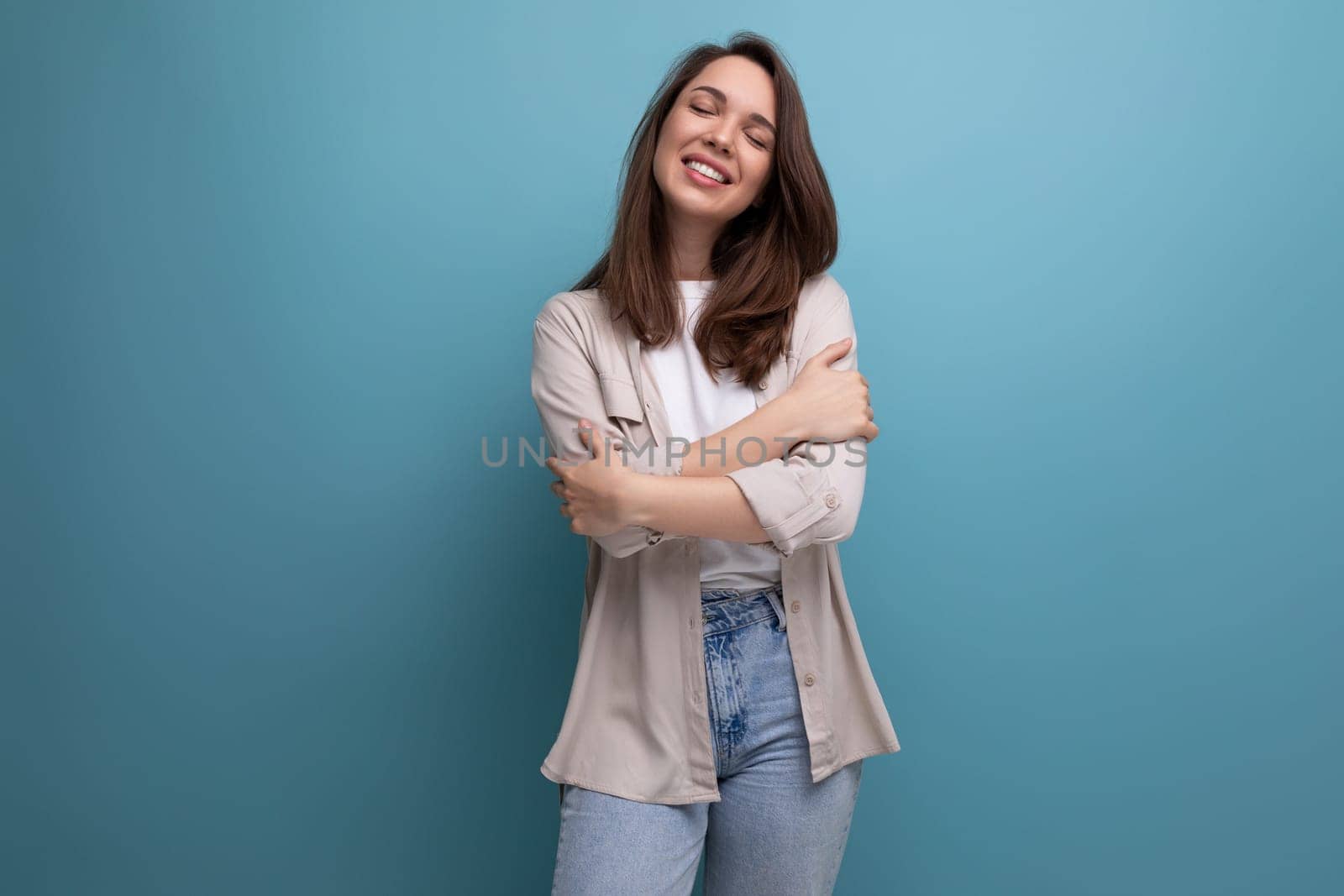 brunette young female adult in shirt and jeans smiling on background with copy space.