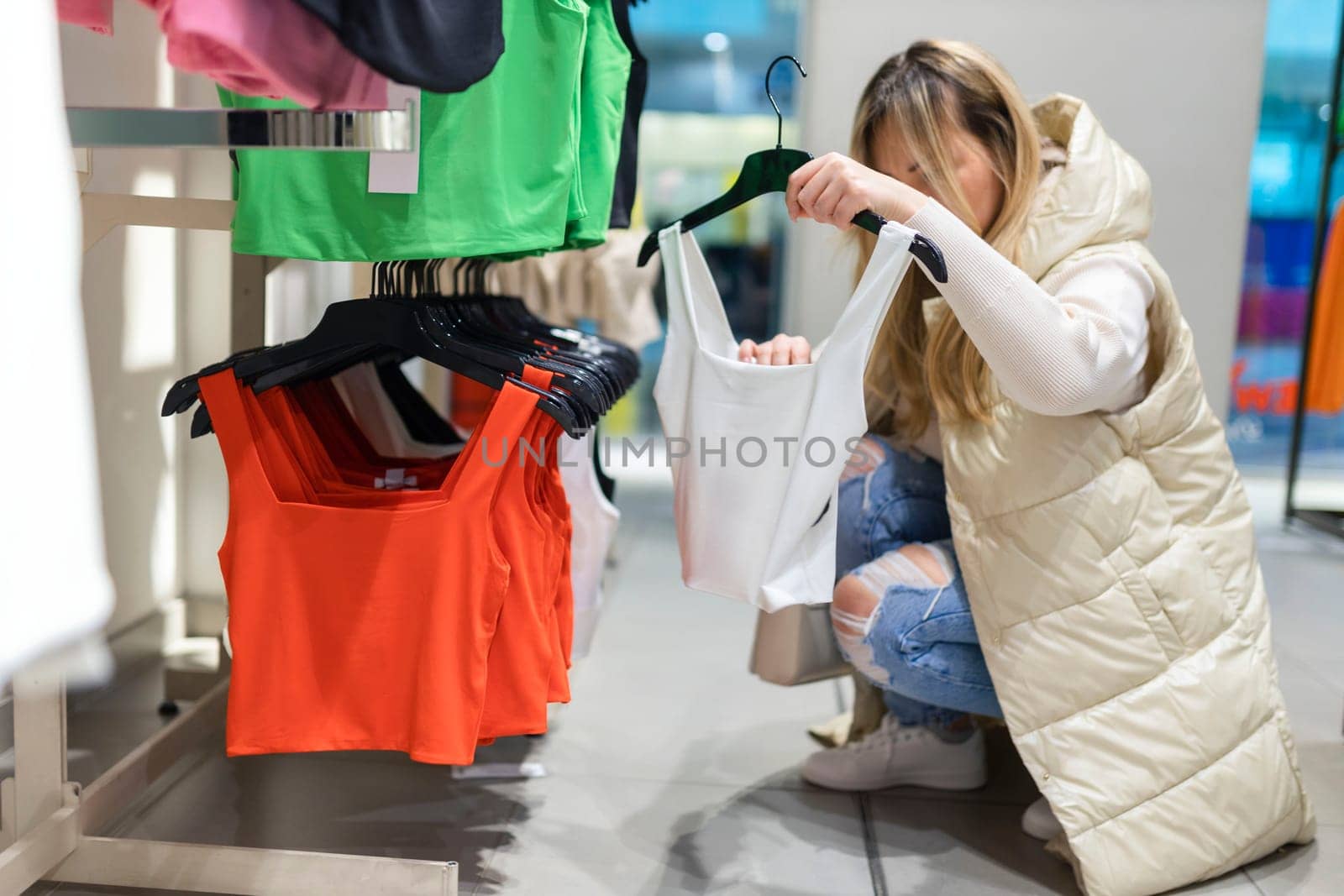 Happy young woman buying new clothes in store. Sale shopping fashion and people concept.