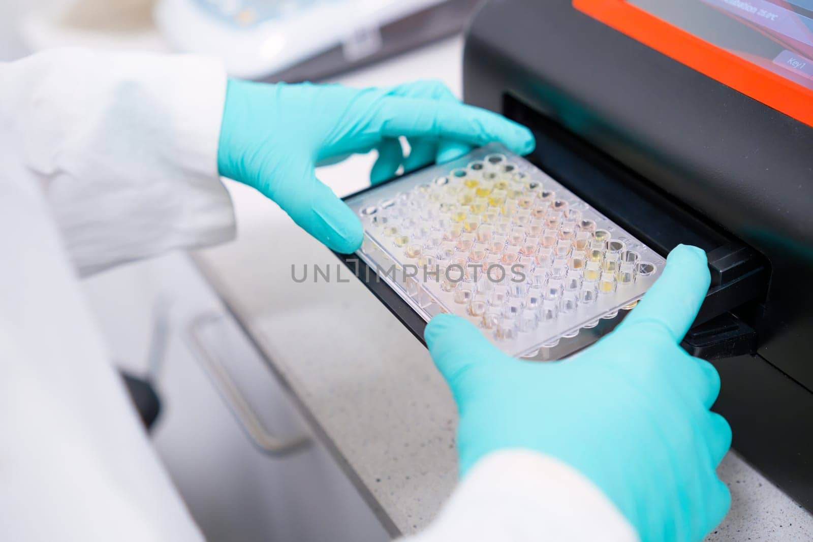 Scientific puts microplate into microplate spectrophotometer to analyze multiple samples for microbiological analysis.