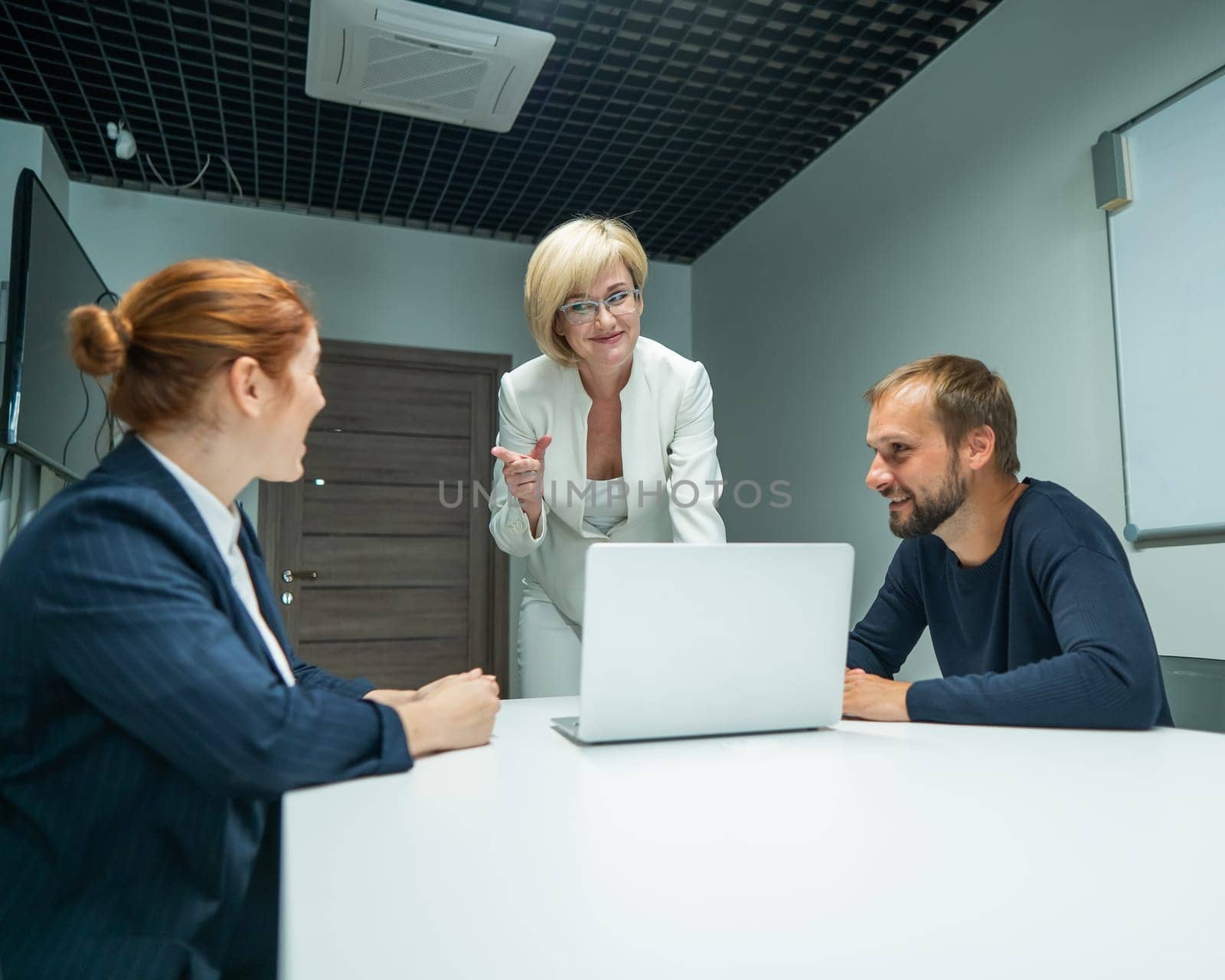 Blond, red-haired woman and bearded man in suits in the office. Business people are negotiating in the conference room. by mrwed54