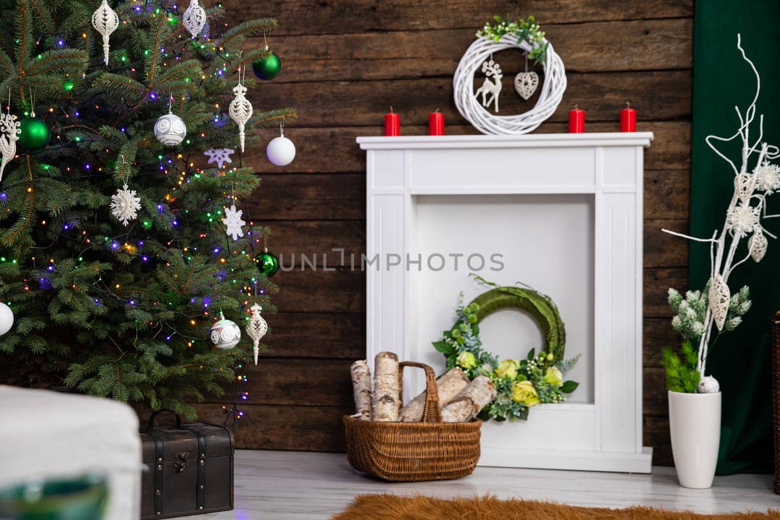 The white fireplace has been decorated to celebrate the upcoming Christmas. A decorated Christmas tree with glowing Christmas lights.
