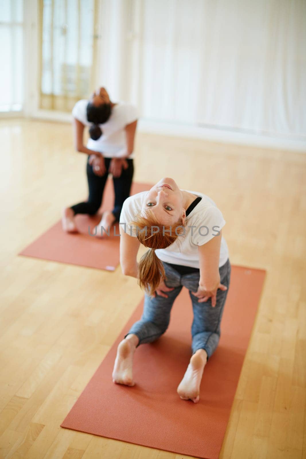 Yoga is part of their daily routine. two women doing yoga together in a studio. by YuriArcurs