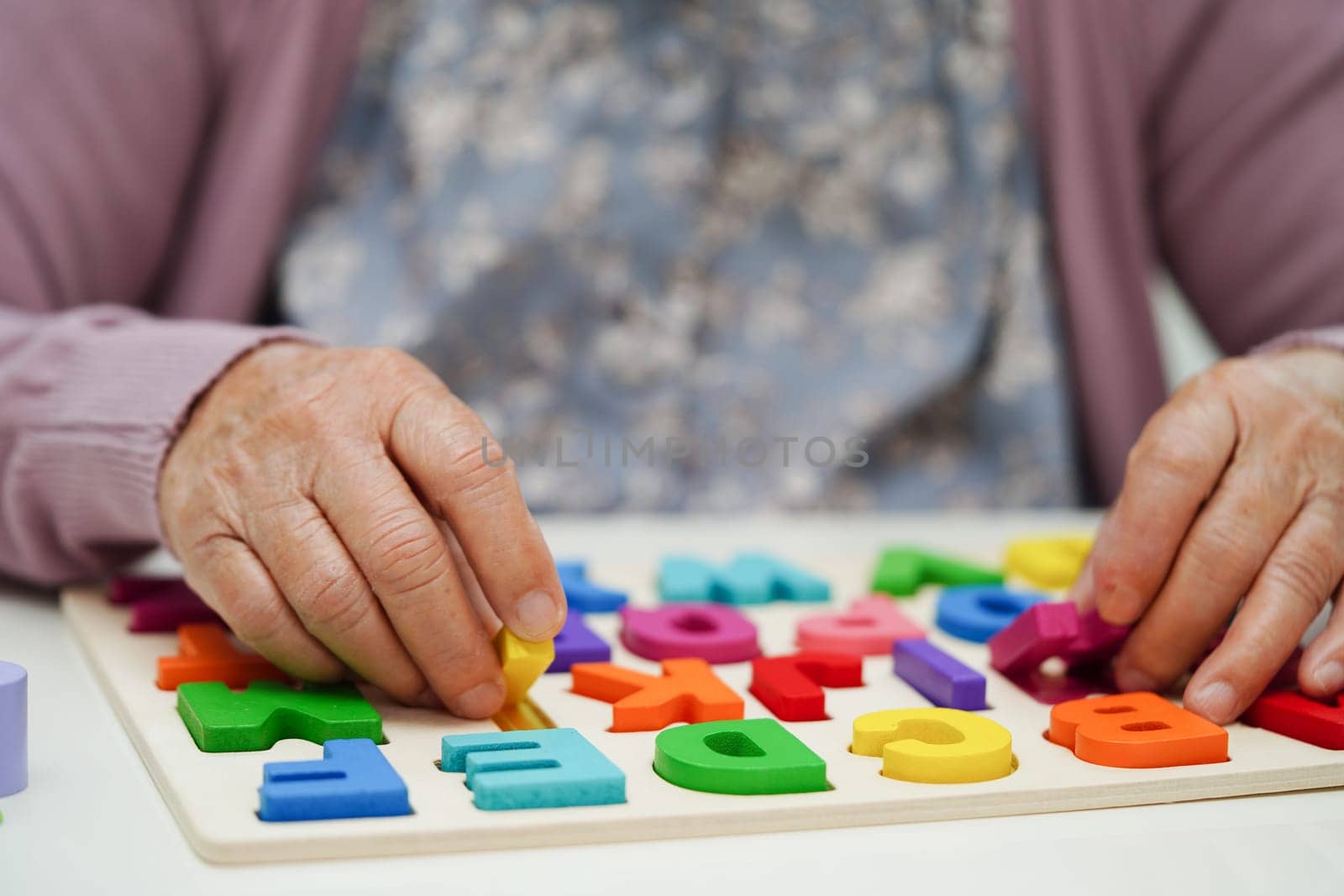 Asian elderly woman playing puzzles game to practice brain training for dementia prevention, Alzheimer disease. by sweettomato