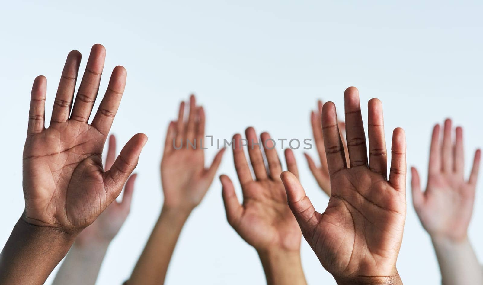 Raise your hands as one. Shot of a group of hands reaching up against a white background. by YuriArcurs