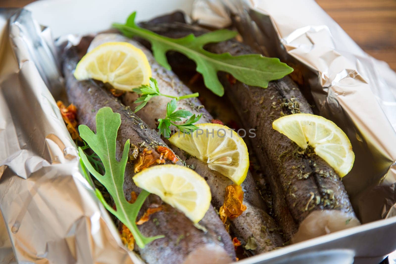 Raw fish with seasonings and spices prepared for baking in foil, in a ceramic form.