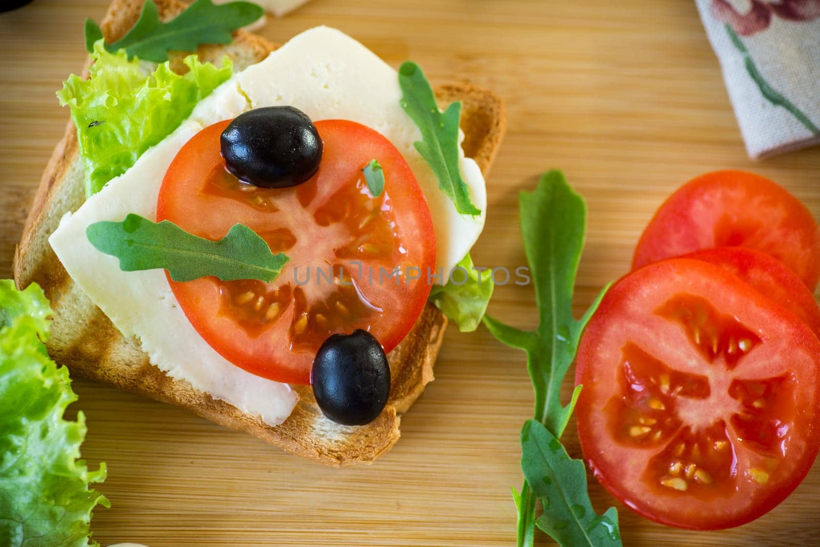 fried toasts with mozzarella, lettuce and tomatoes with herbs on a wooden table