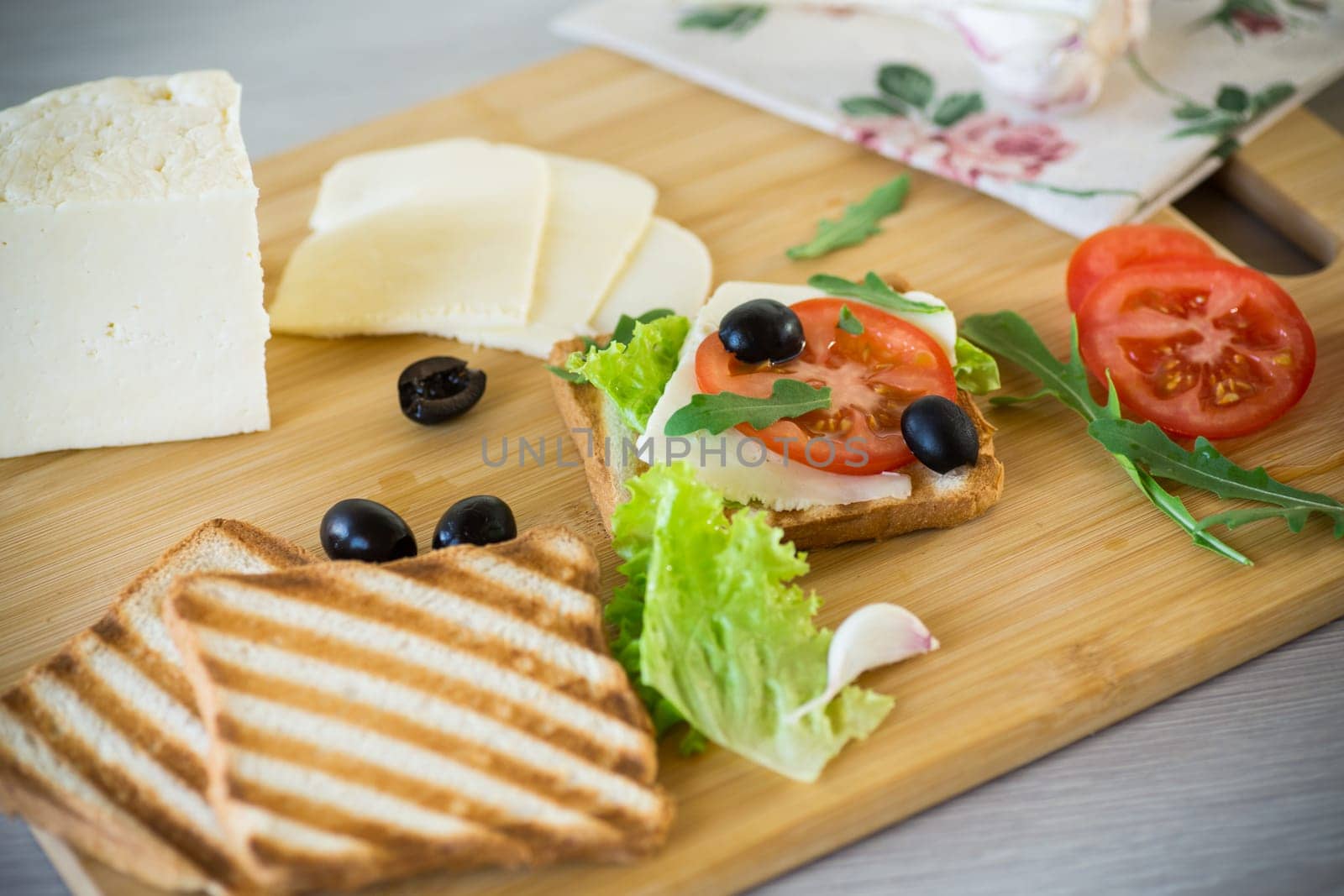 fried toasts with mozzarella, lettuce and tomatoes with herbs on a wooden table