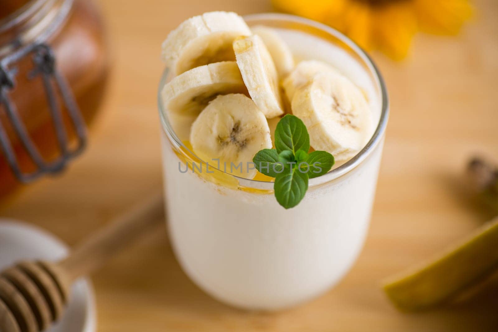 Sweet homemade yogurt with bananas and honey in a glass