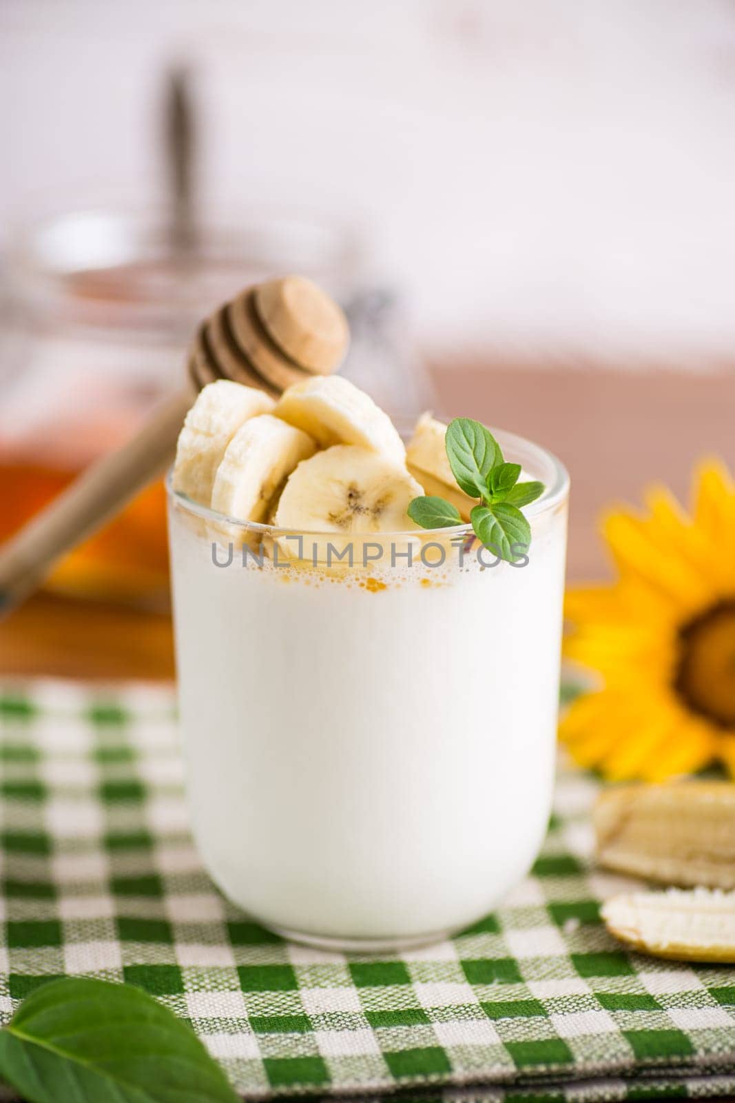 Sweet homemade yogurt with bananas and honey in a glass