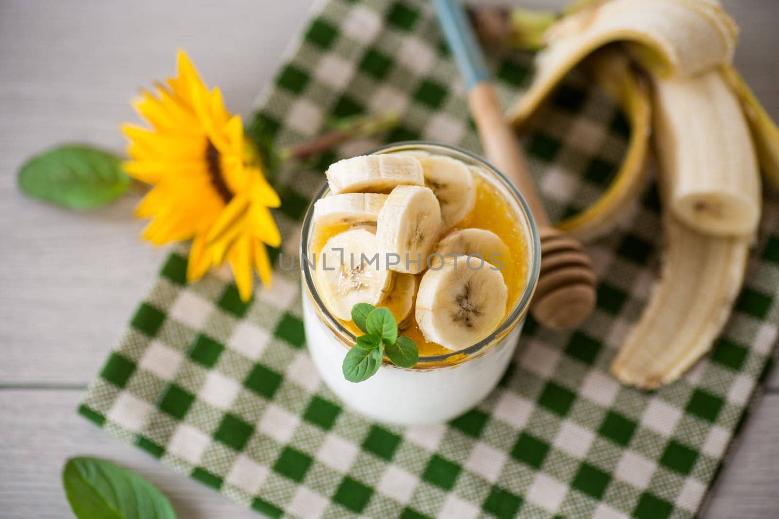 Sweet homemade yogurt with bananas and honey in a glass