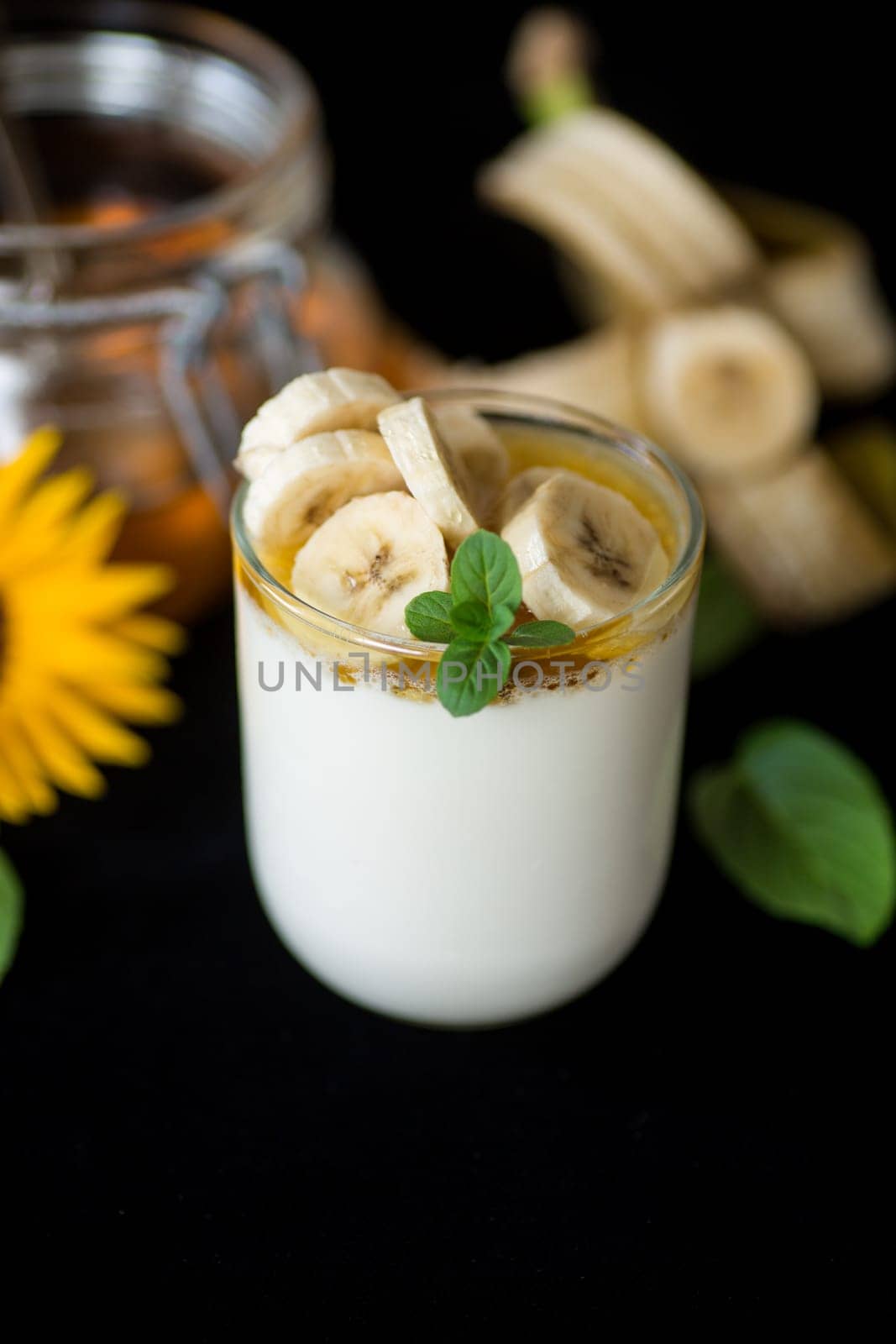 Sweet homemade yogurt with bananas and honey in a glass