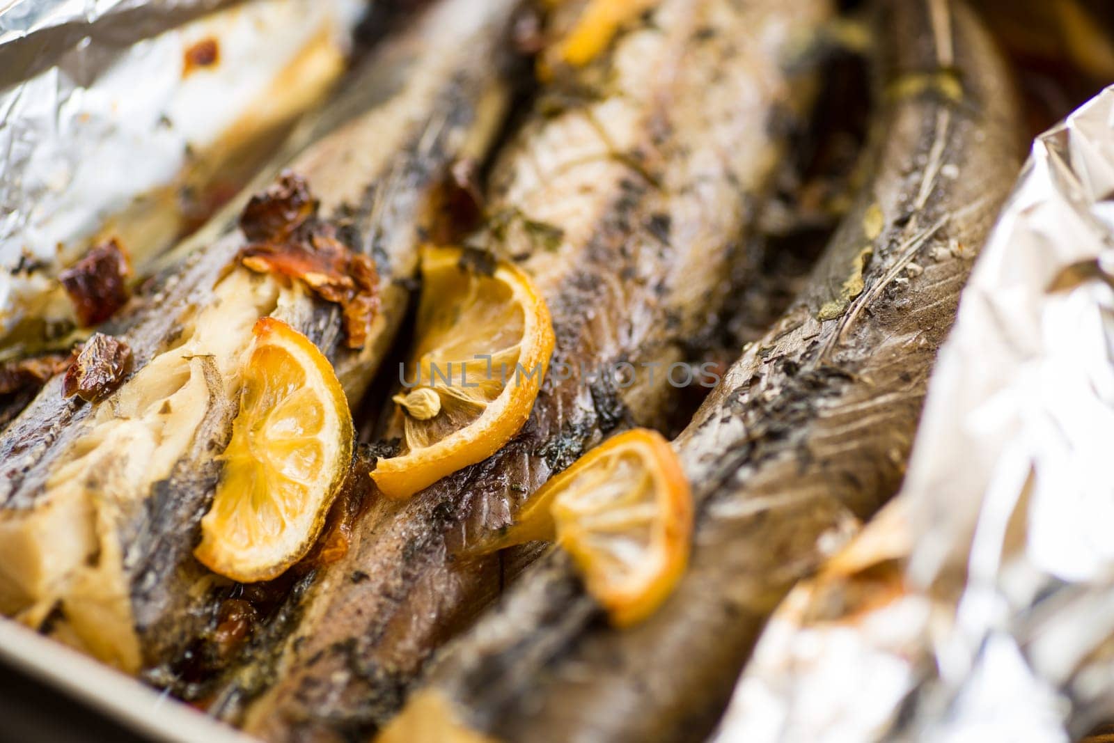 Baked fish with seasonings and spices in foil, in a ceramic form.