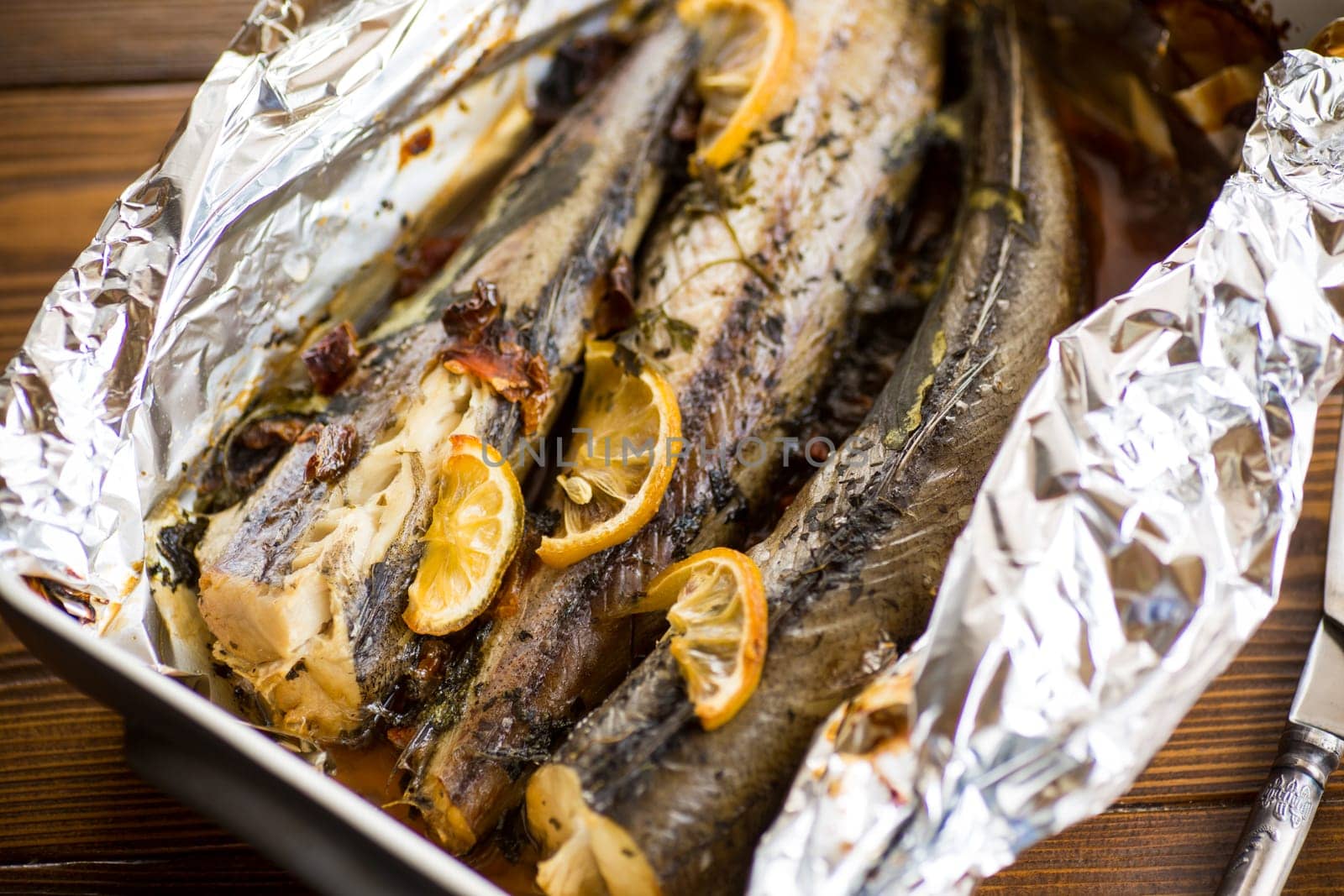 Baked fish with seasonings and spices in foil, in a ceramic form.