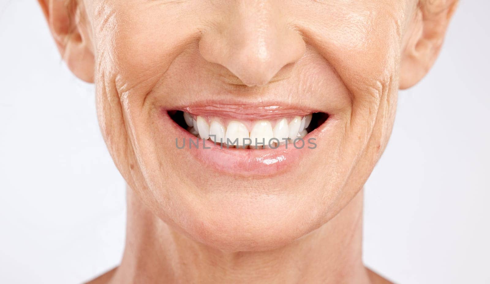 Teeth, mouth and smile of a senior woman with dental cleaning against a grey studio background. Dentist, wellness and elderly model with healthcare and happy with results from veneers for beauty by YuriArcurs