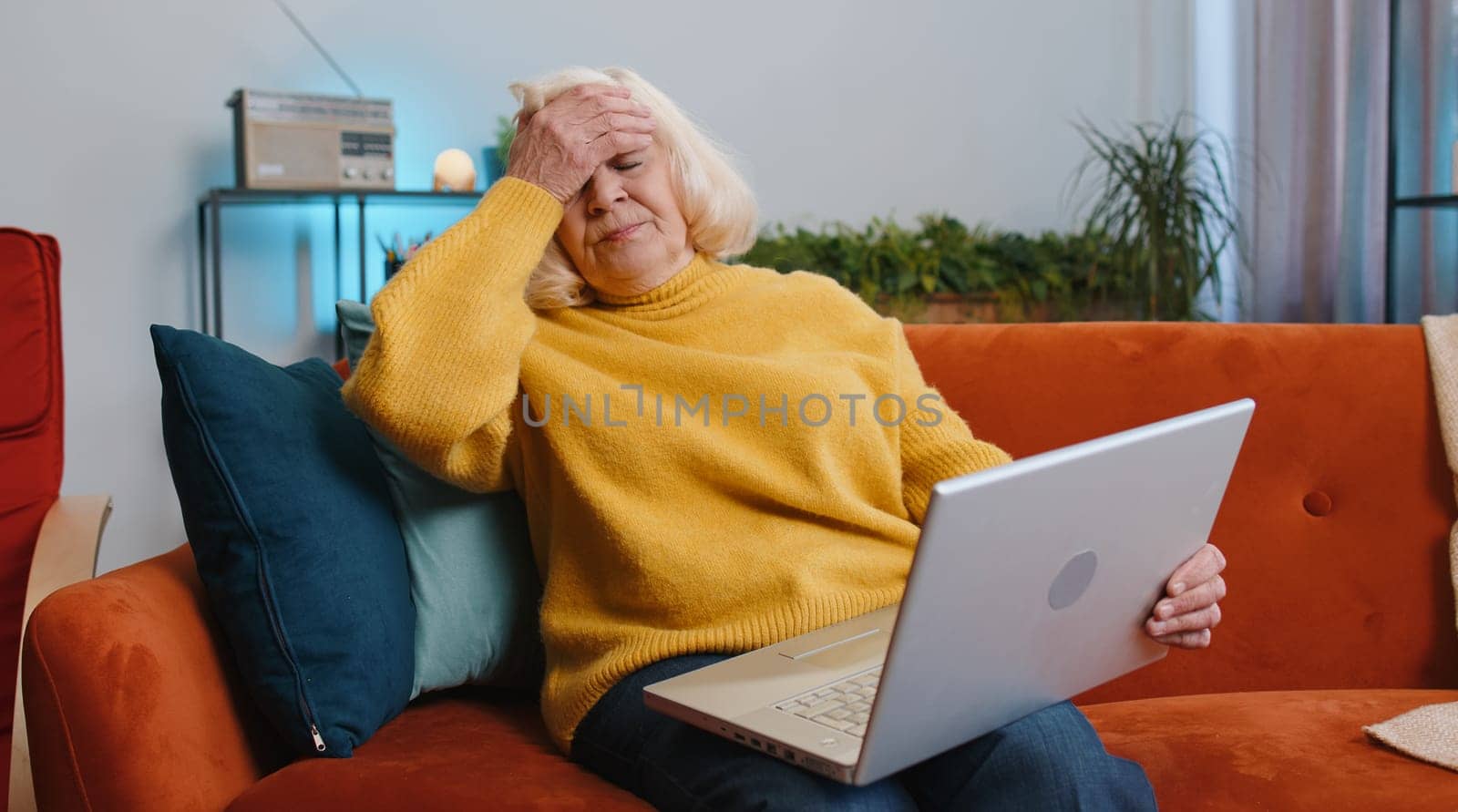 Tired senior woman use laptop, suffering from headache problem tension and migraine, stress at home. Elderly grandmother works on notebook, sends messages, makes online purchases, watching movies