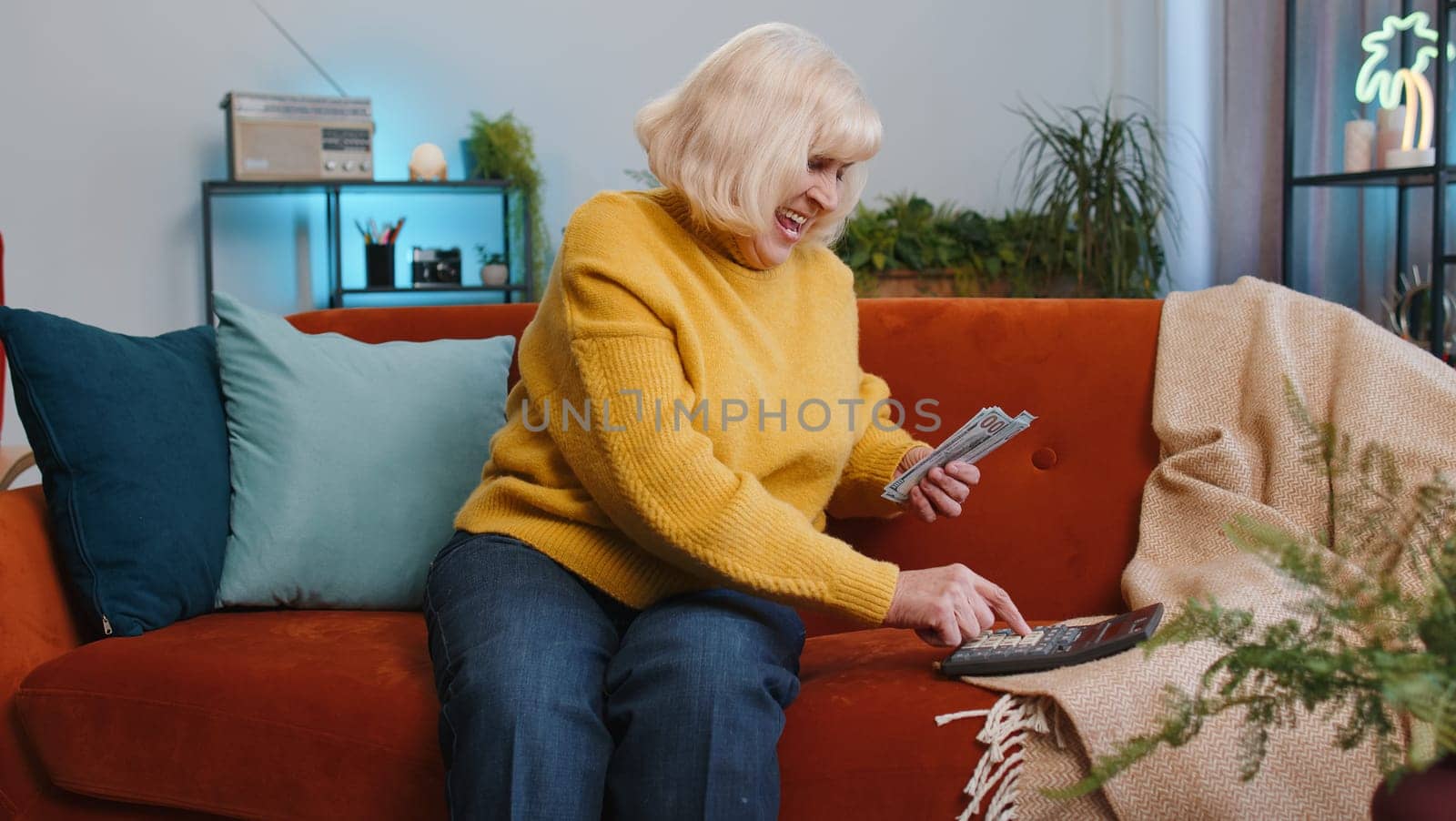 Planning budget. Rich senior woman counting money cash use calculator, calculate domestic bills at home. Elderly grandmother satisfied of income earnings win, saves money for planned vacation, gifts