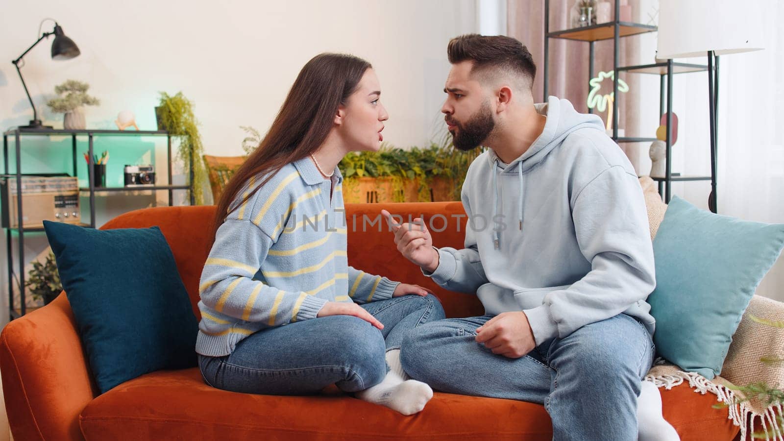 Aggressive family married couple man woman quarreling, shouting at each other at home. Divorce, conflict problem, crisis, distribution of property. Irritated husband and wife on sofa in living room
