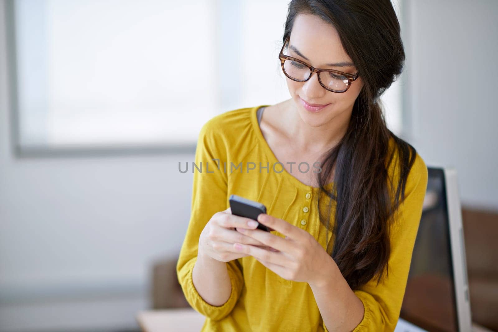 Communication is important in any workplace. an attractive young woman using a cellphone in an office. by YuriArcurs