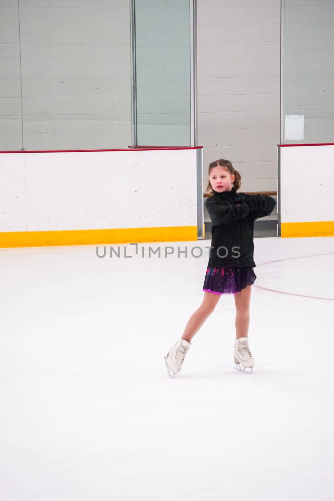 Little girl practicing before her figure skating competition at the indoor ice rink.