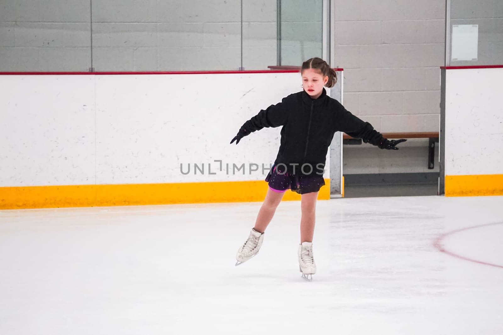 Little girl practicing before her figure skating competition at the indoor ice rink.