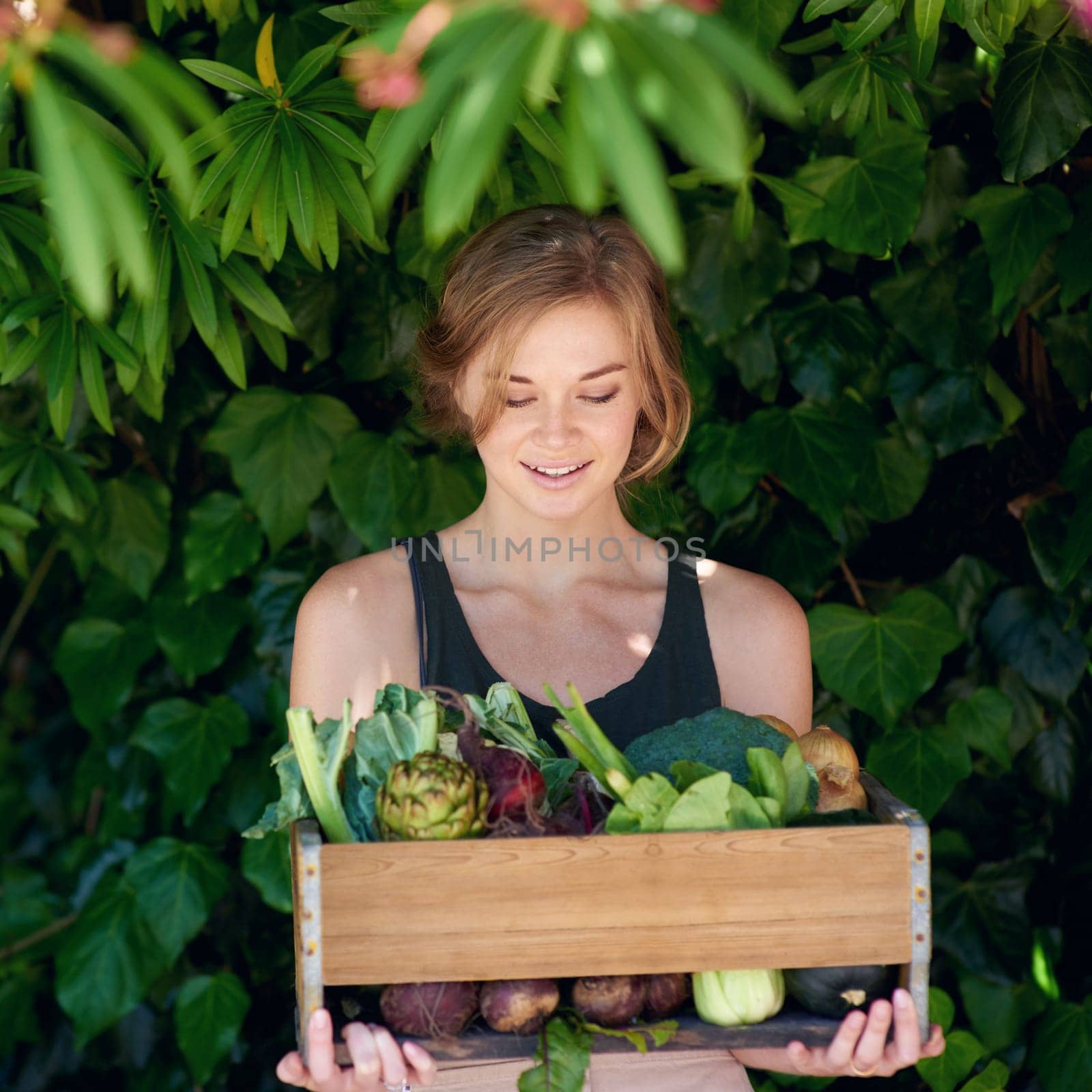 Let food be thy medicine and medicine be thy food. A young woman holding a crate of vegetables outdoors. by YuriArcurs