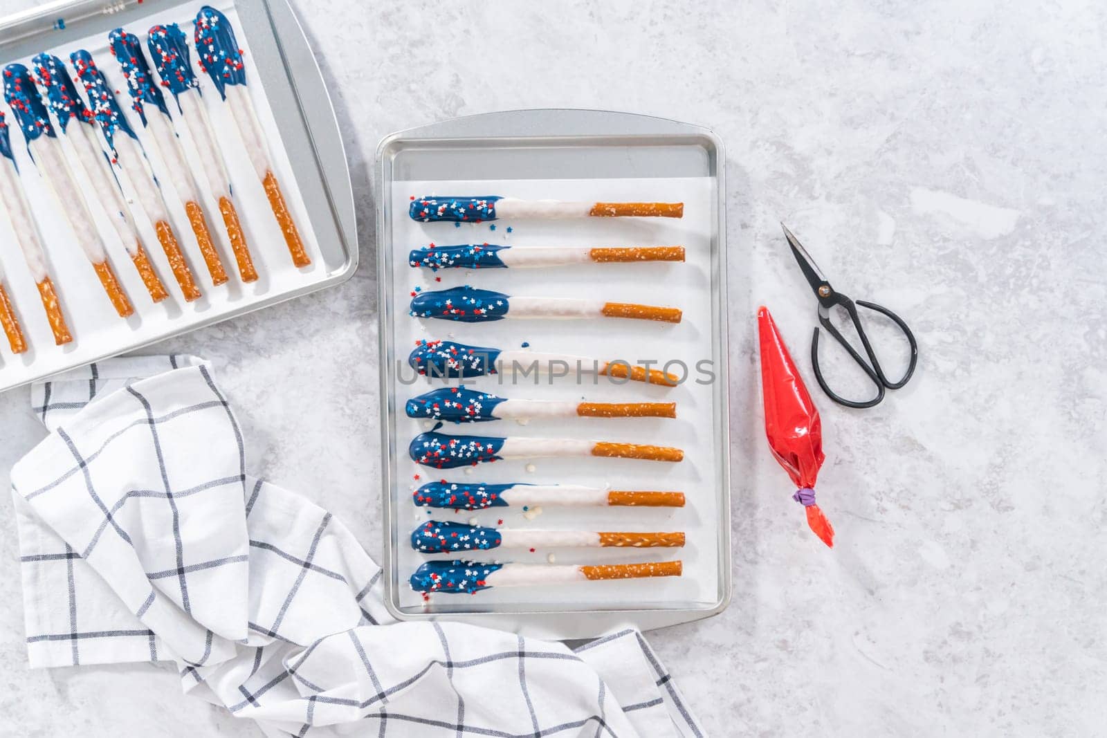 Flat lay. Dipping pretzel rods into the melted chocolate to prepare chocolate dipped pretzel rods for the July 4th celebration.