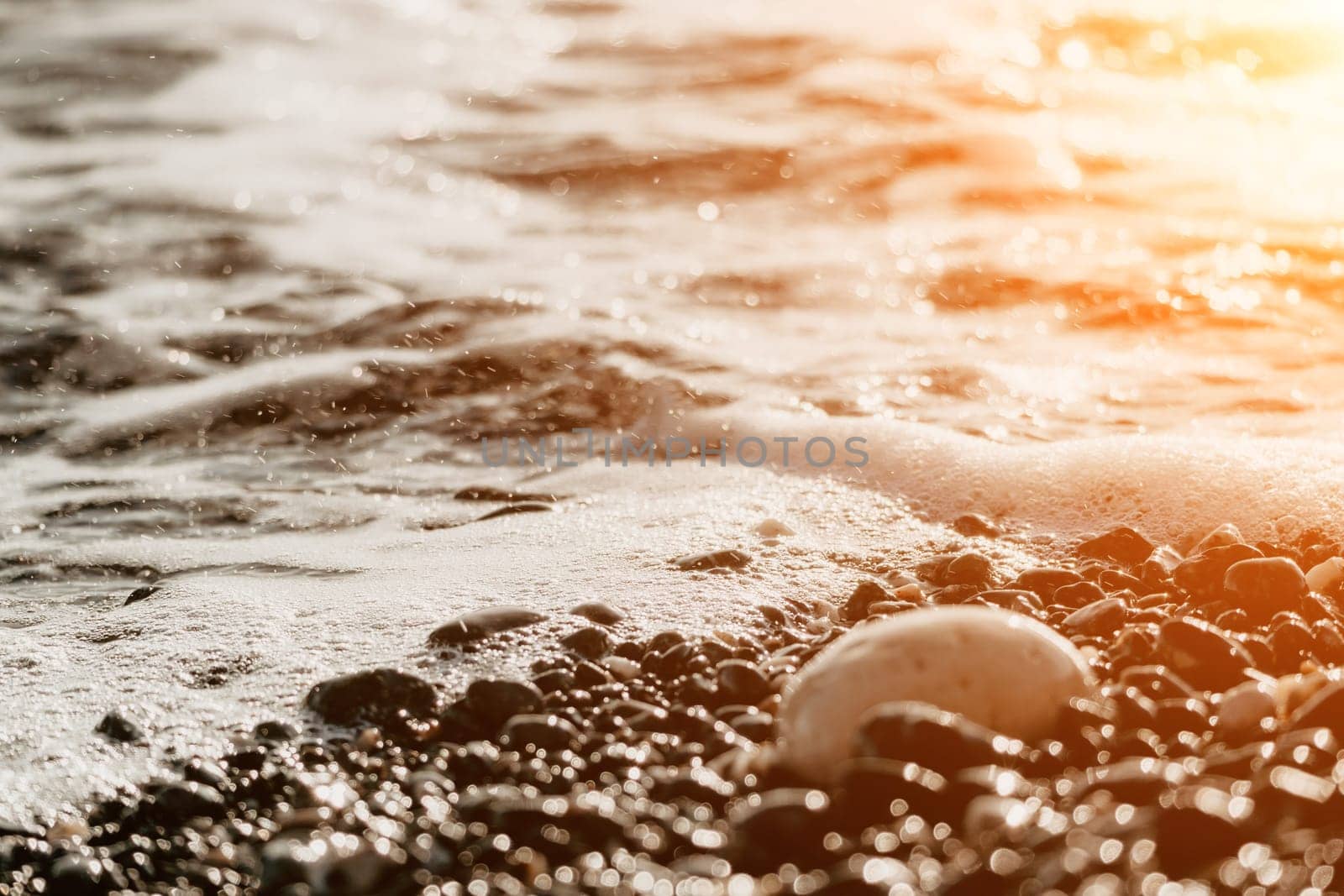 Abstract sea summer ocean sunset nature background. Small waves on golden water surface in motion blur with golden bokeh lights from sun. Holiday, vacation and recreational concept.