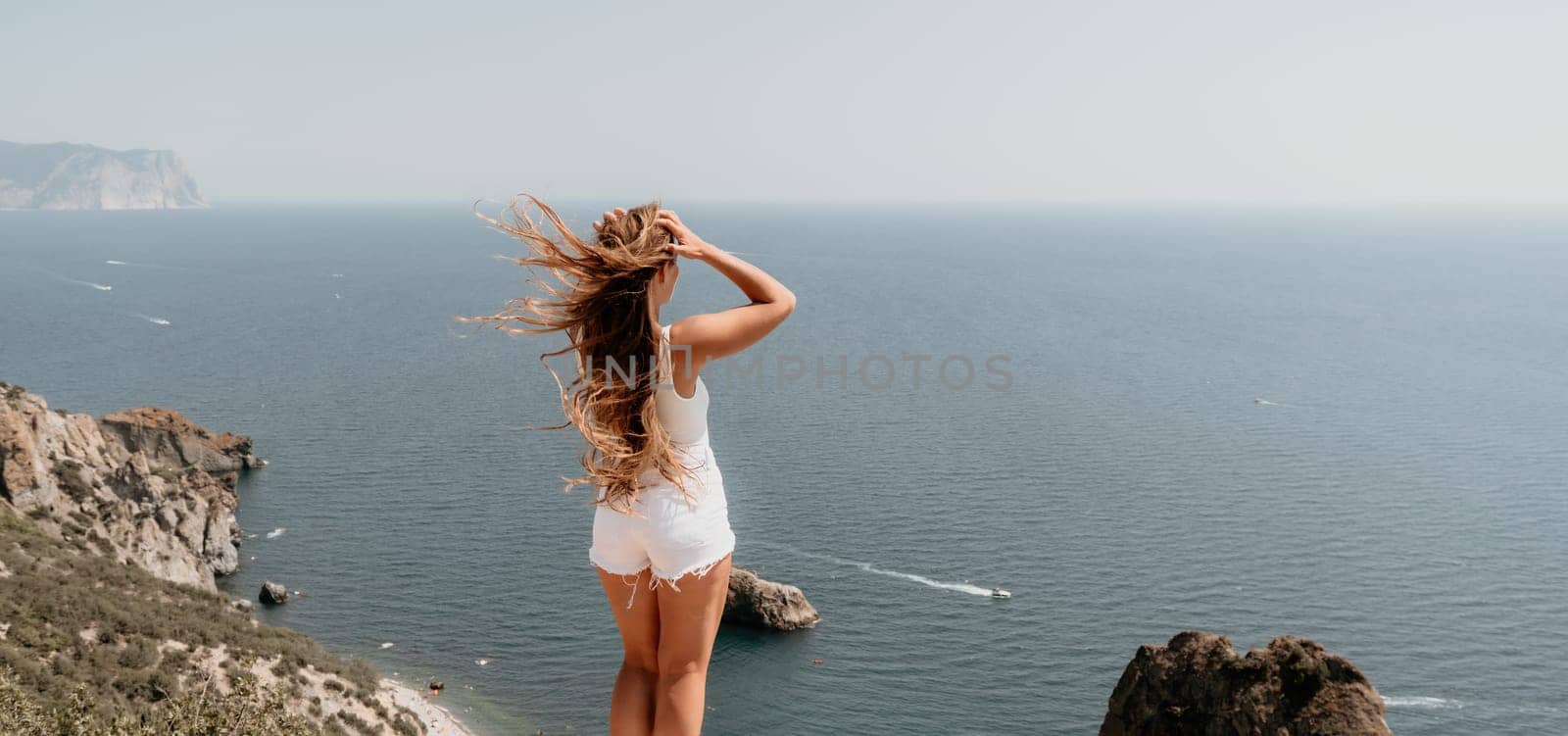 Woman summer travel sea. Happy tourist enjoy taking picture outdoors for memories. Woman traveler posing over sea bay surrounded by volcanic mountains, sharing travel adventure journey by panophotograph