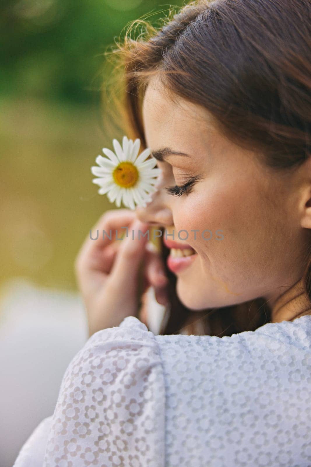 close-up portrait of a woman with a chamomile flower on the background of the lake. High quality photo