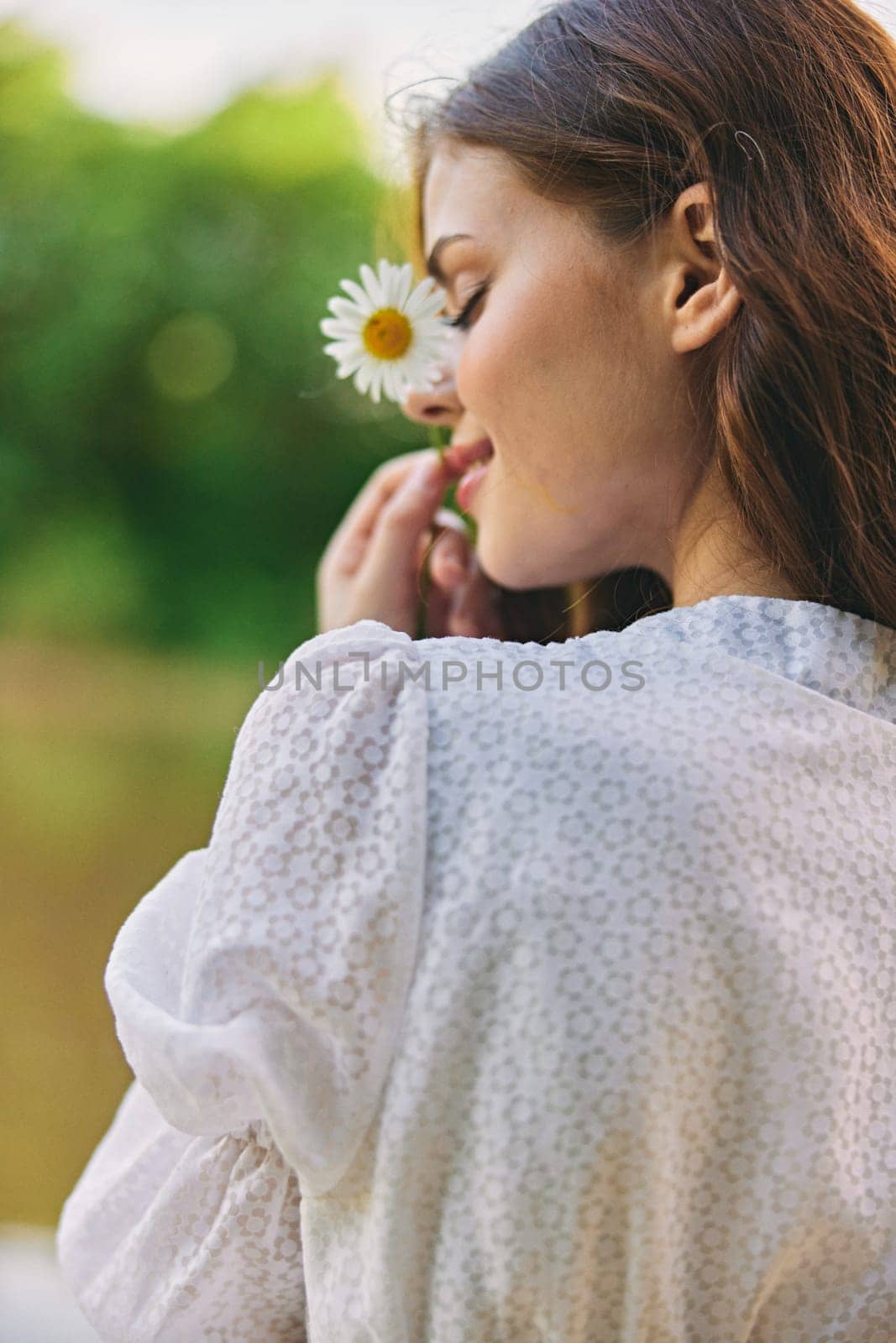 close-up portrait of a woman with a chamomile flower on the background of the lake. High quality photo