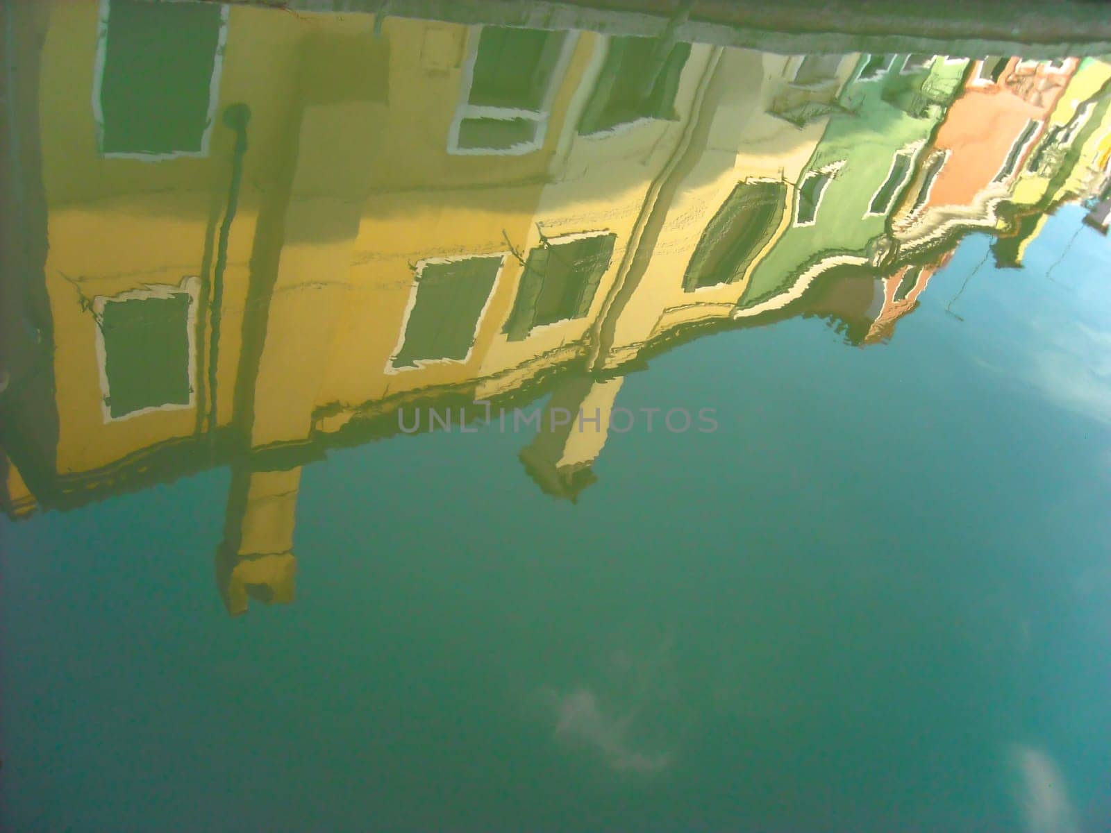 The characteristic colored houses of Burano (Venice) reflected on the water of a canal