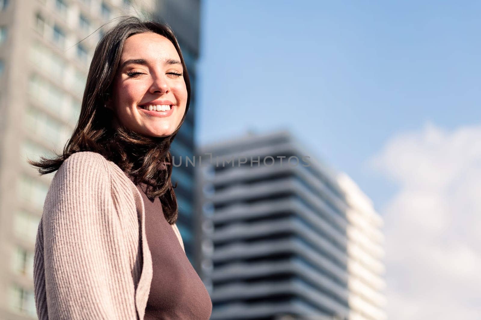 smiling young woman looking at camera on sunny day at city, concept of happiness and urban lifestyle, copy space for text