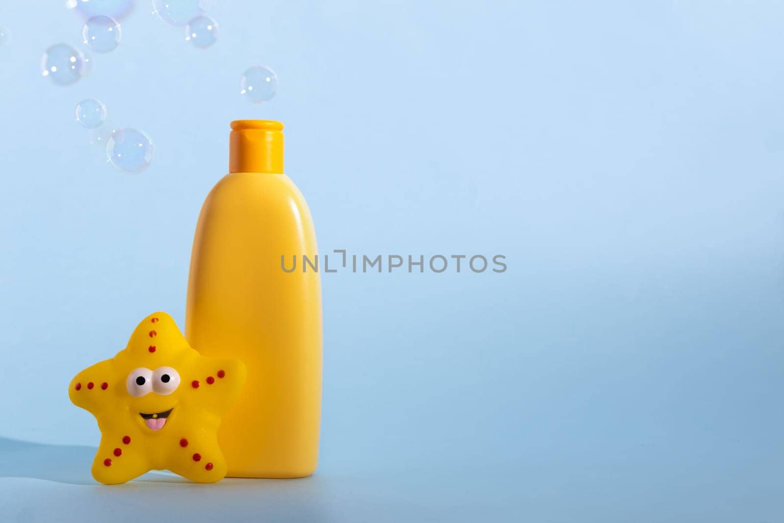 Mockup of a yellow bottle of baby washing gel, bath foam, liquid soap or shampoo with yellow star fish and flying soap bubbles. Kid's hygiene. Template for design. by Ri6ka